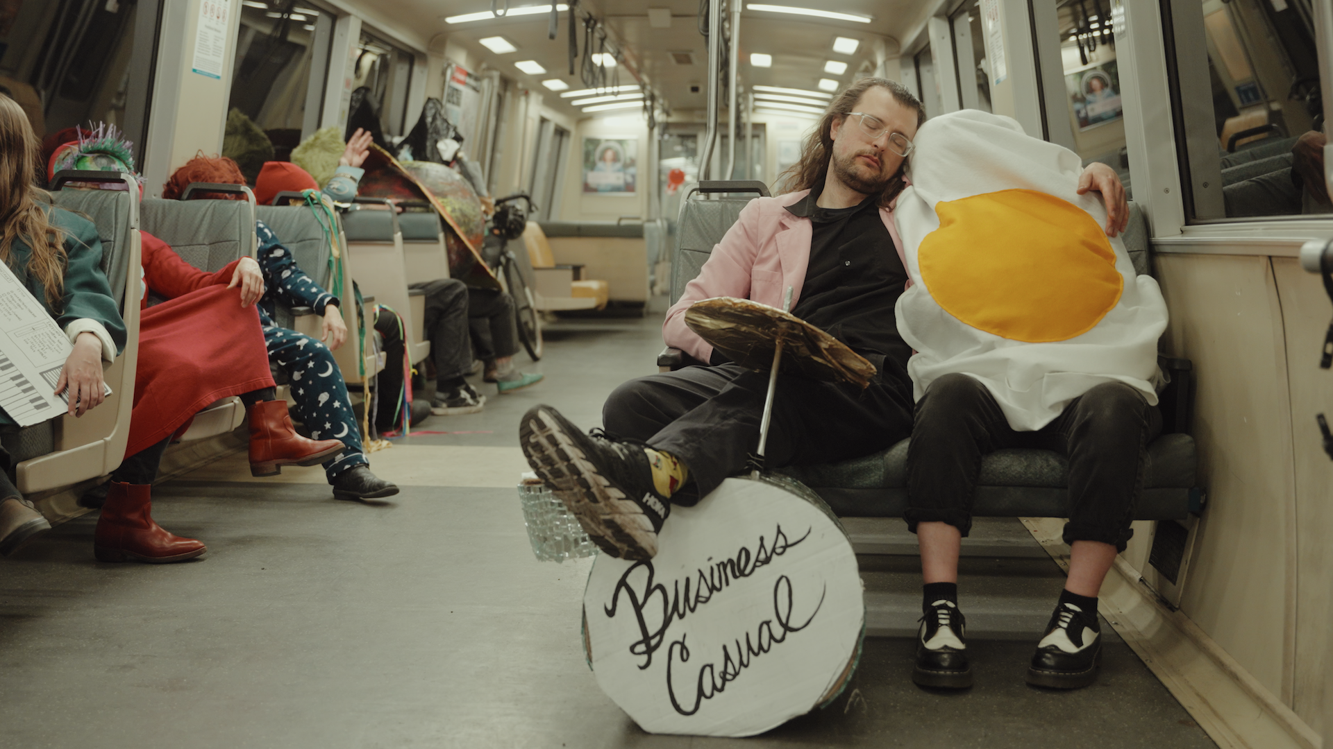 Photo of a person holding another person in an egg costume as they sit on the BART train