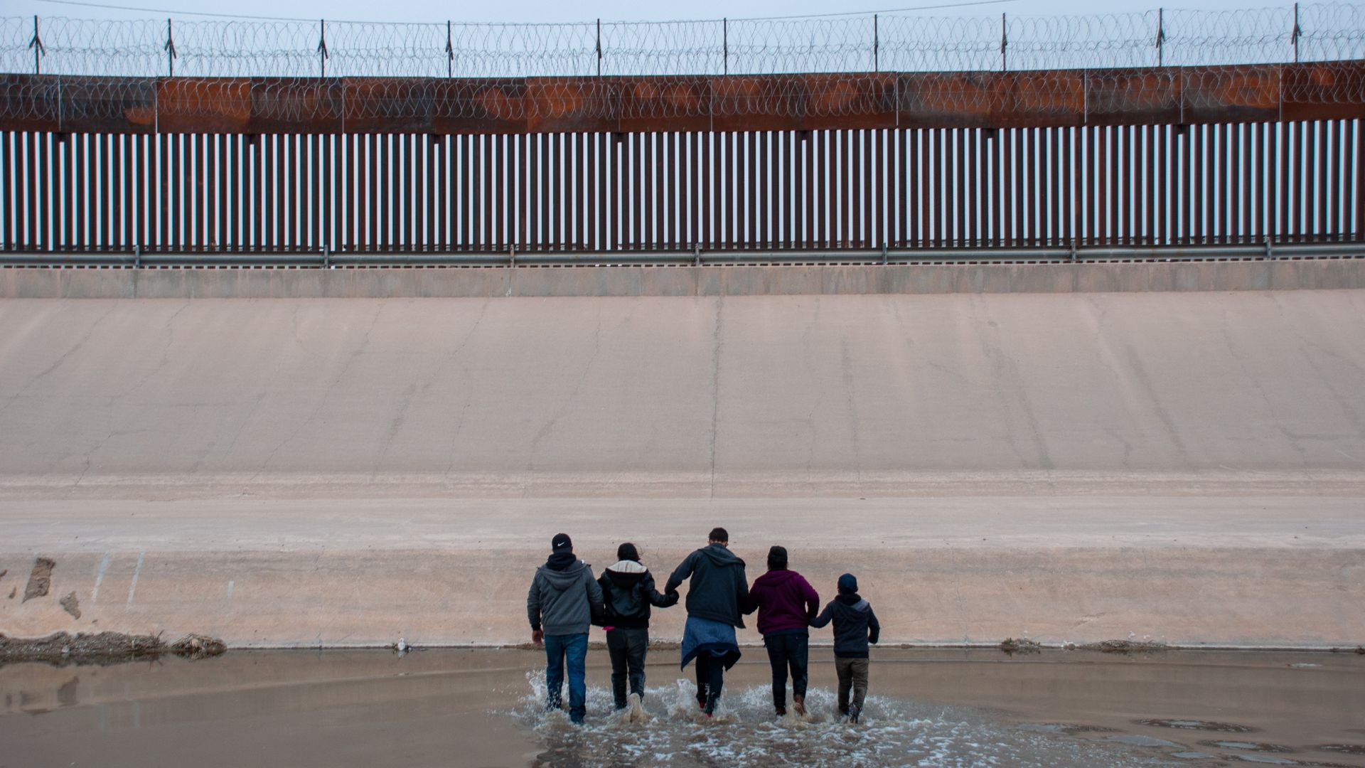 A group of migrants is seen crossing a river at the border between the United States and Mexico.