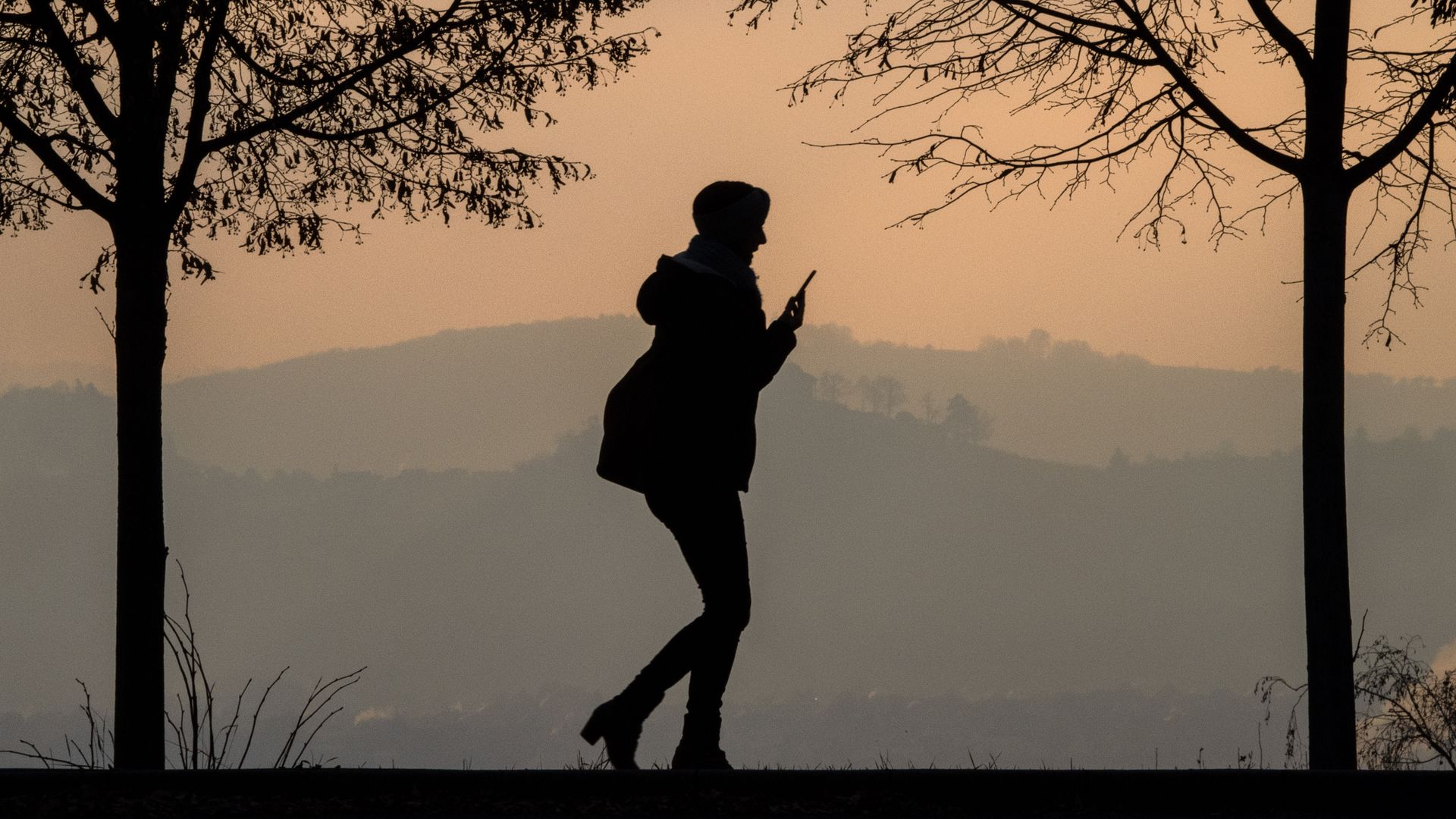A shadowy profile of a woman looking at a phone
