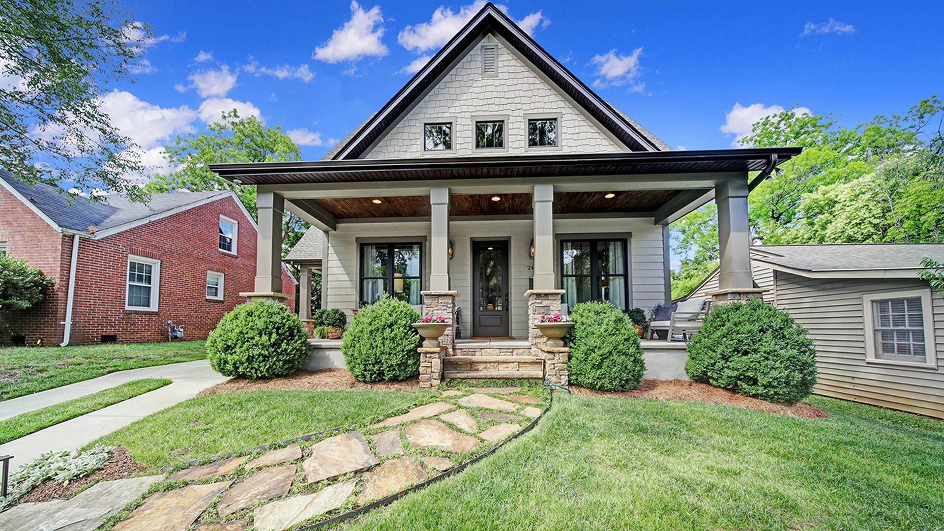 home with large front porch and four pillars out front with a curved stone walkway leading to it