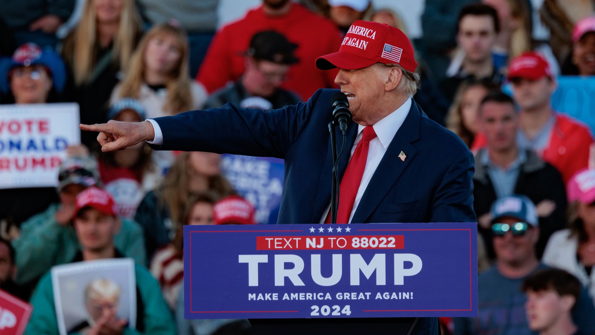 Former President Donald Trump points to the left as he speaks onstage at a campaign rally.