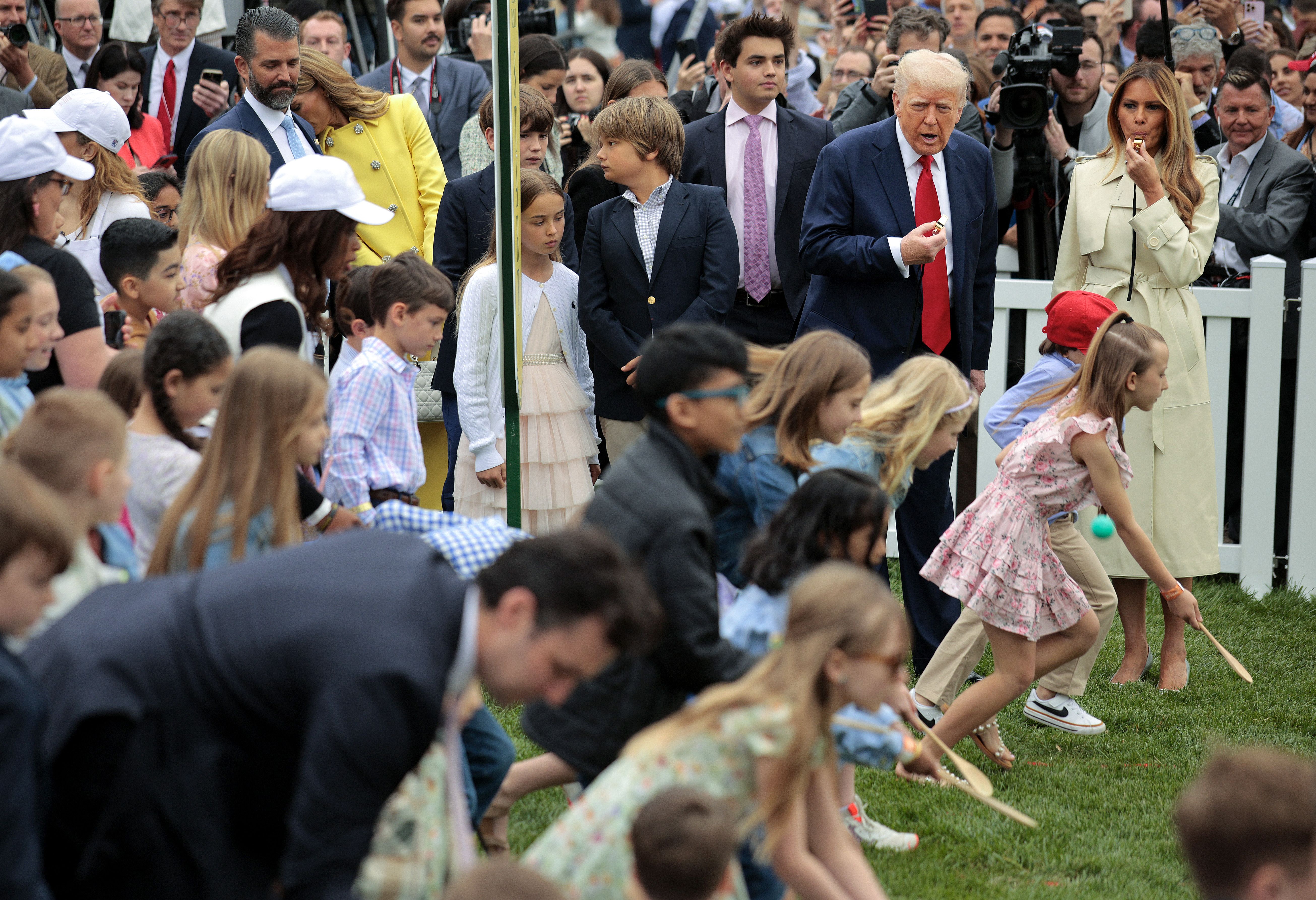 Children race with eggs and wooden spoons during the White House Egg Roll as Melania Trump blows a whistle.