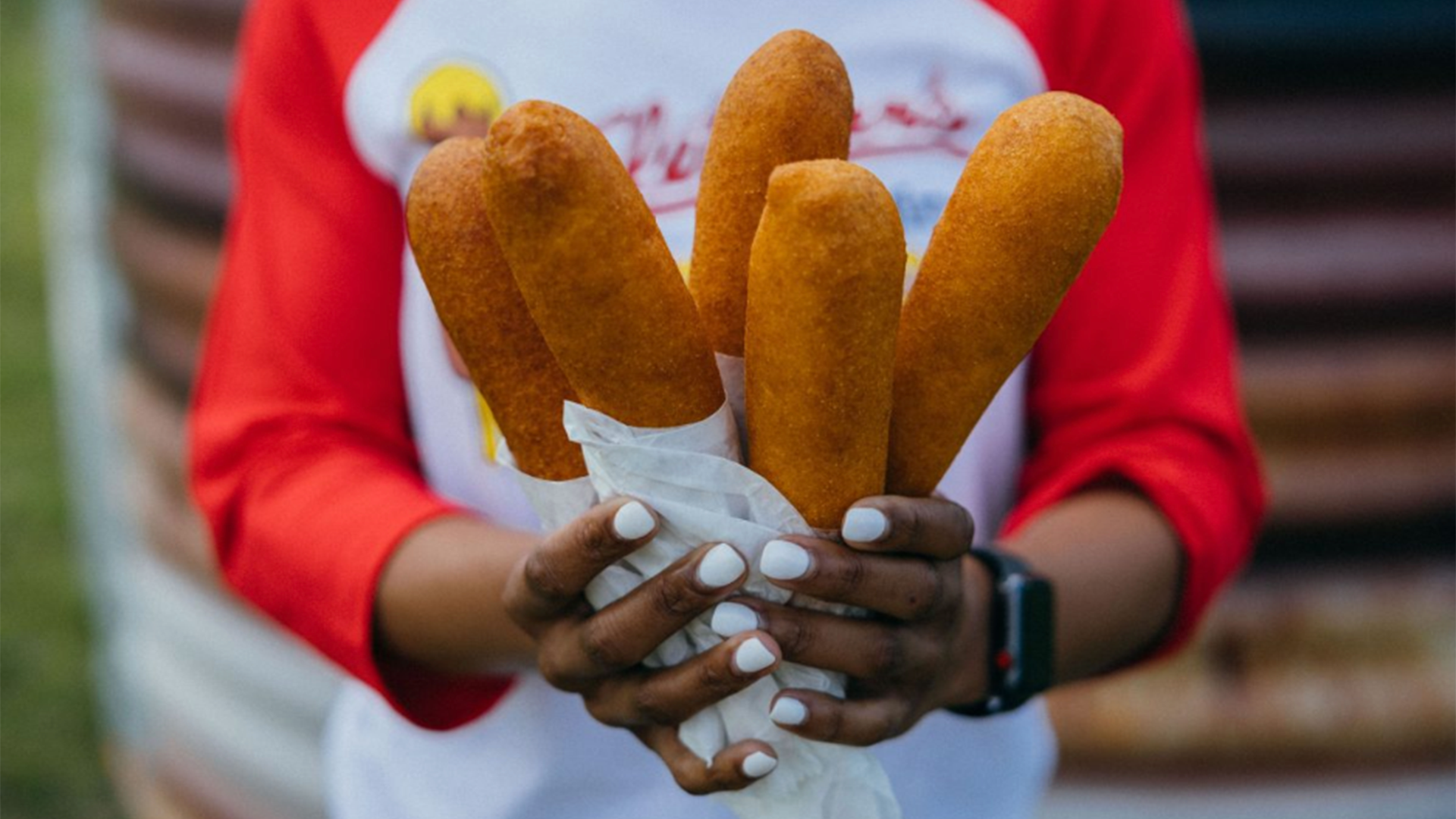 a person holds a bundle of corn dogs