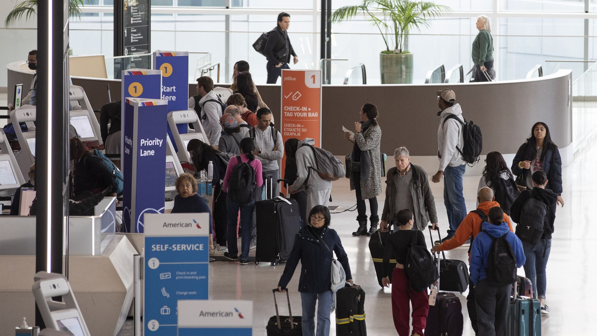 About a dozen passengers at the airport in the checkin area. Photo taken from slightly above