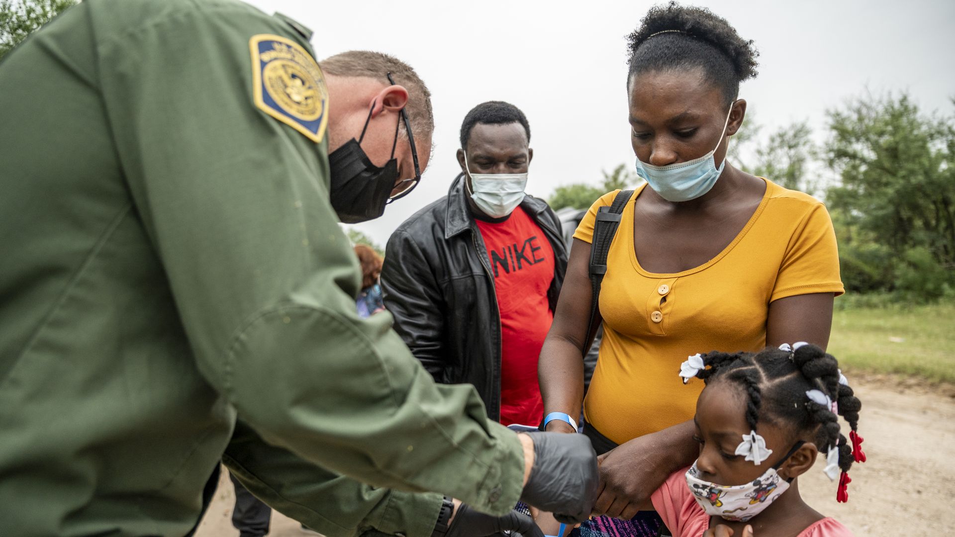 Picture of Haitian migrants standing by a border agent