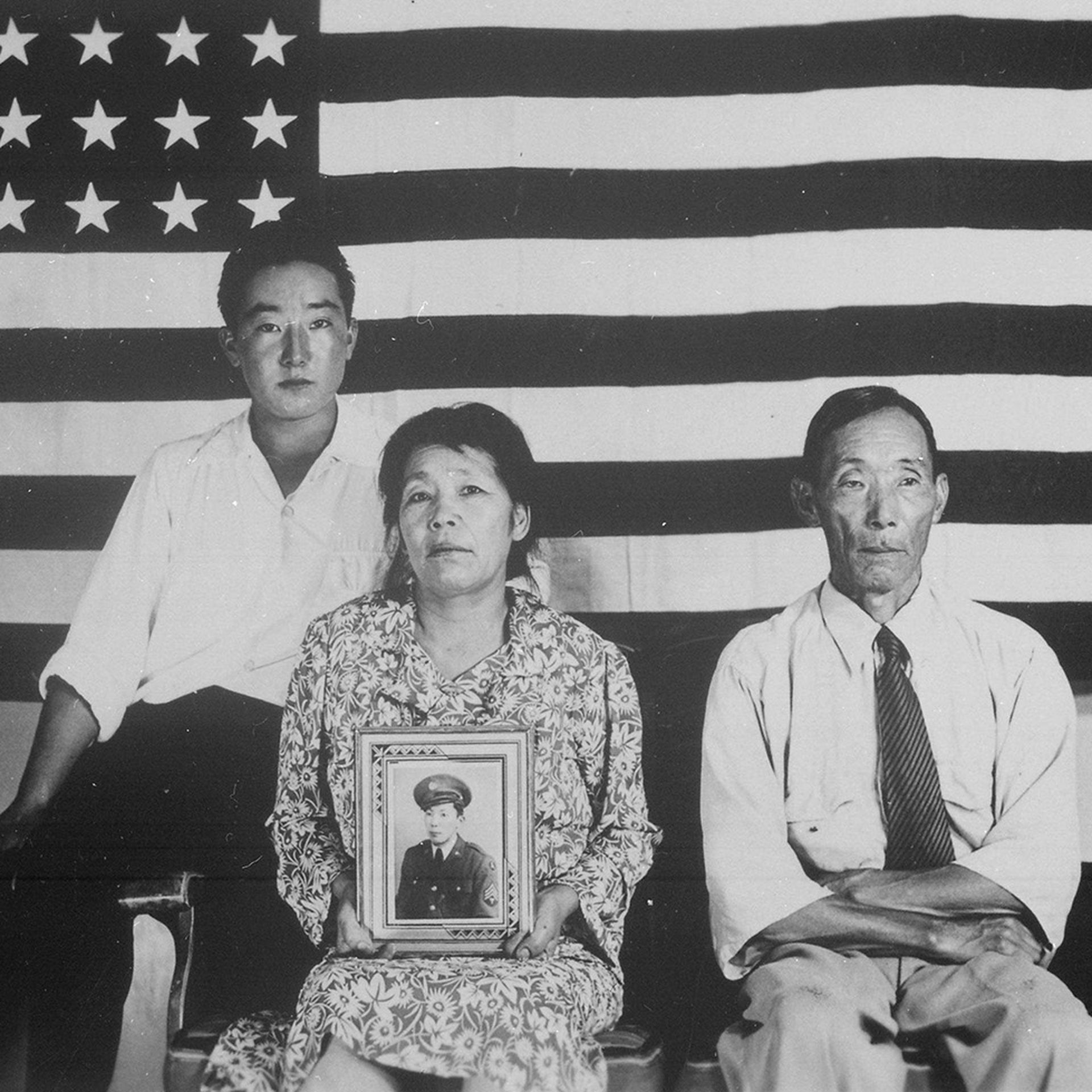 A family of three sits in front of the American flag