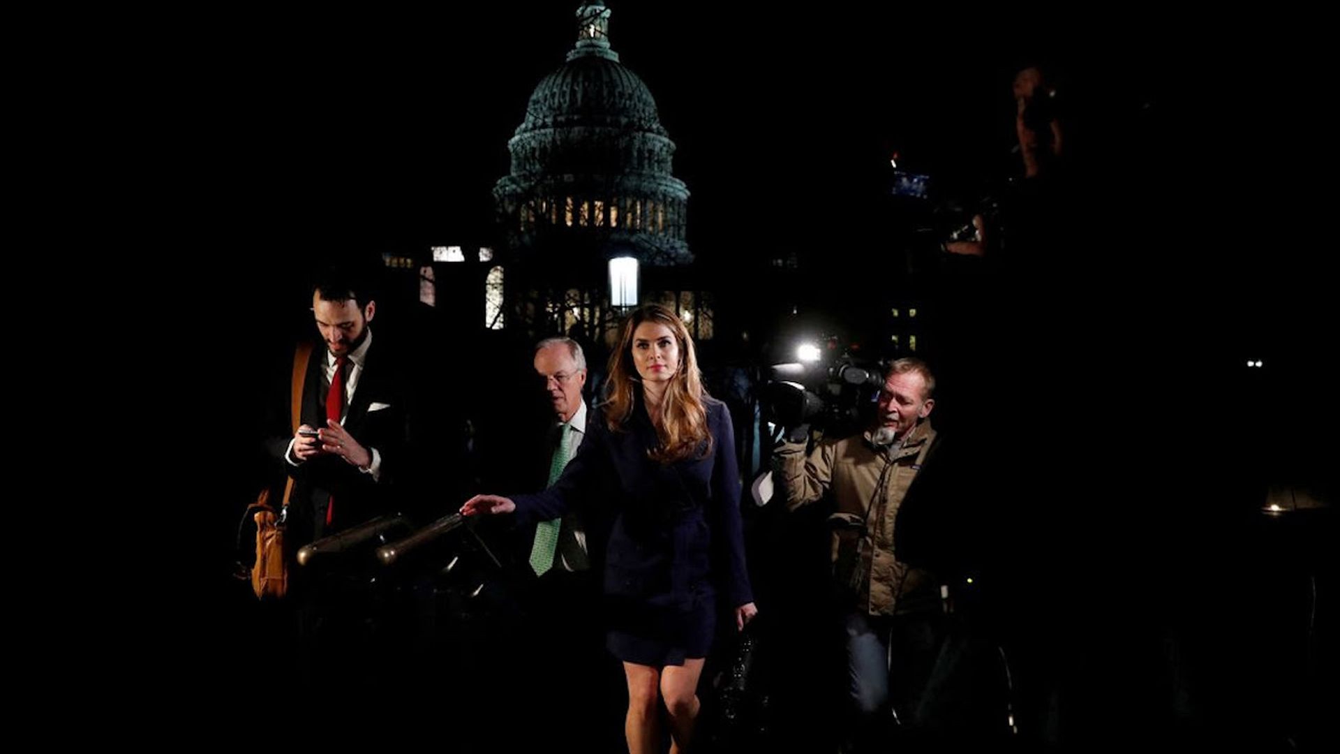 Hope Hicks walking as she's about to fling her suitcase with a crowd behind her