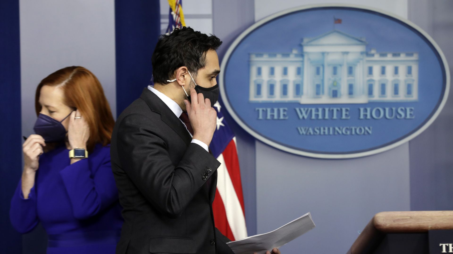 Two White House staffers are seen adjusting their masks as they pass in the West Wing.