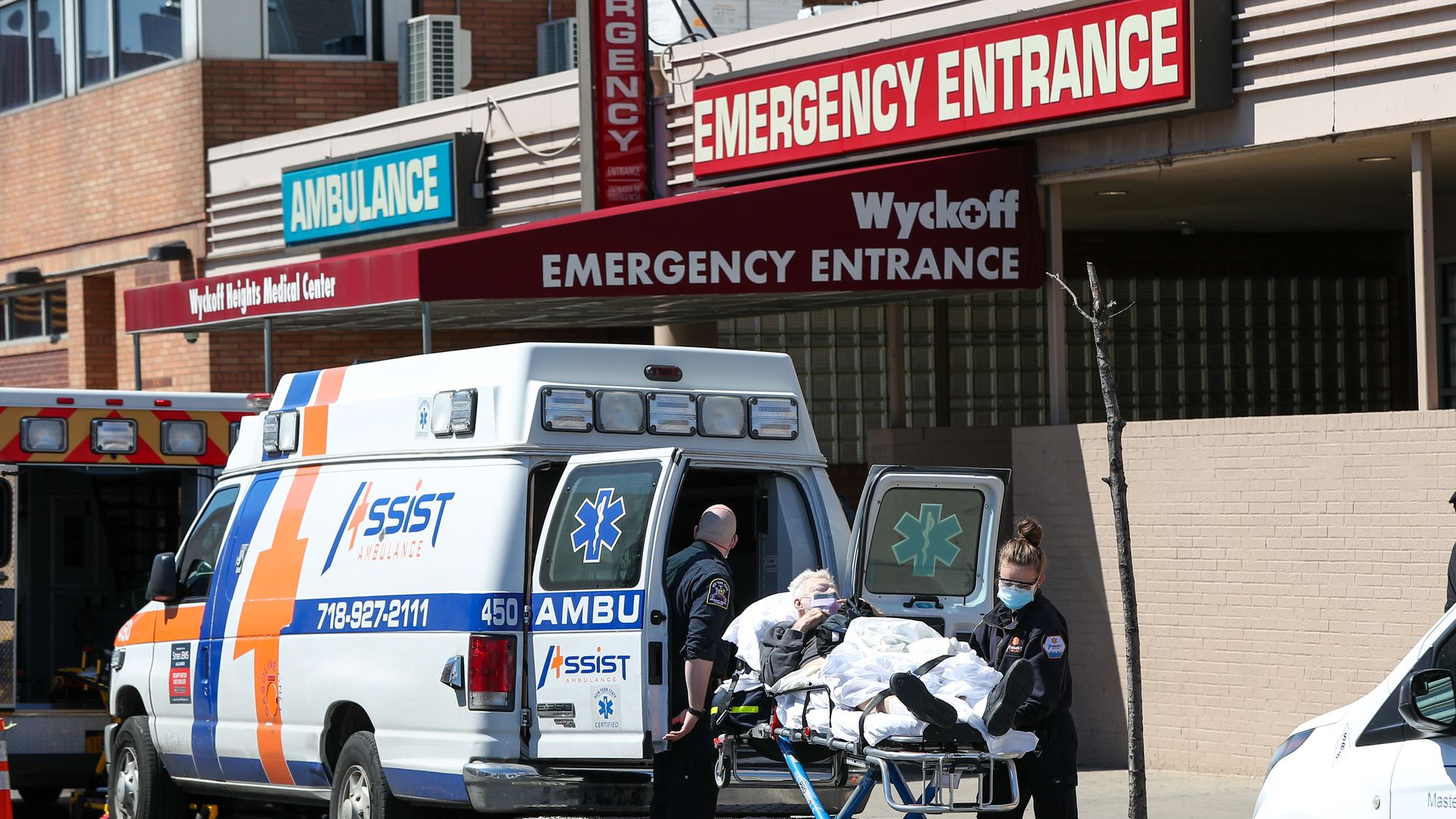 Medics wheel a coronavirus patient on a gurney outside a hospital emergency room.