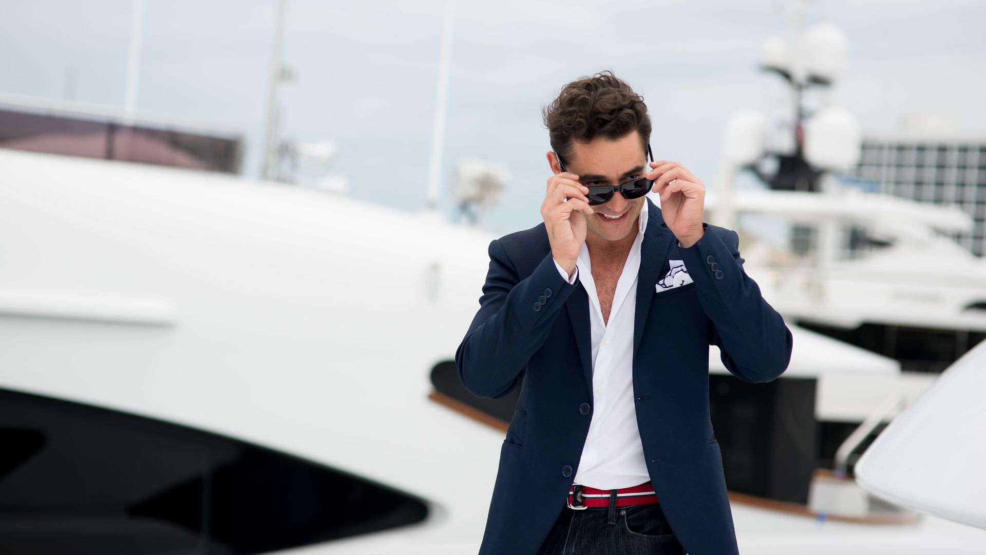 A man in a suit in front of a yacht 