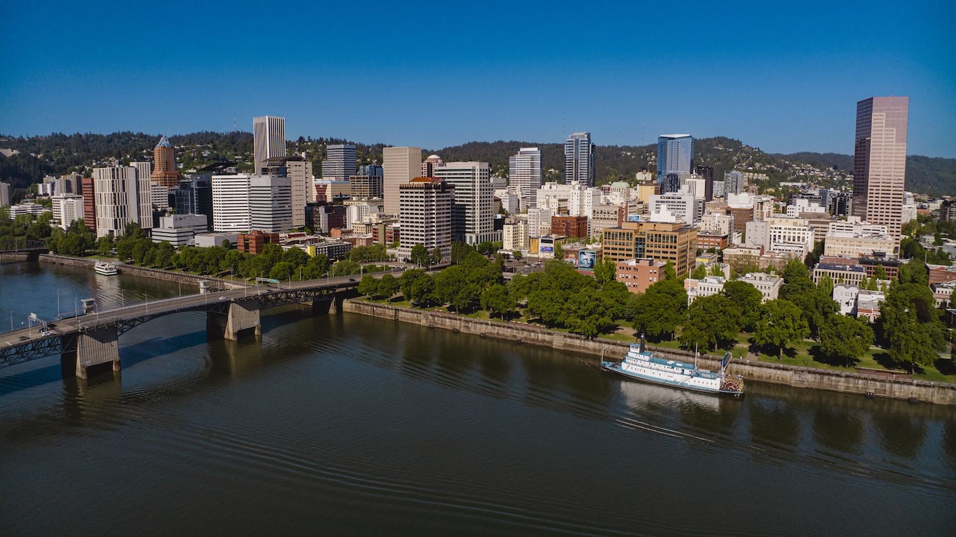 A photo of a city skyline with a bridge over a river.