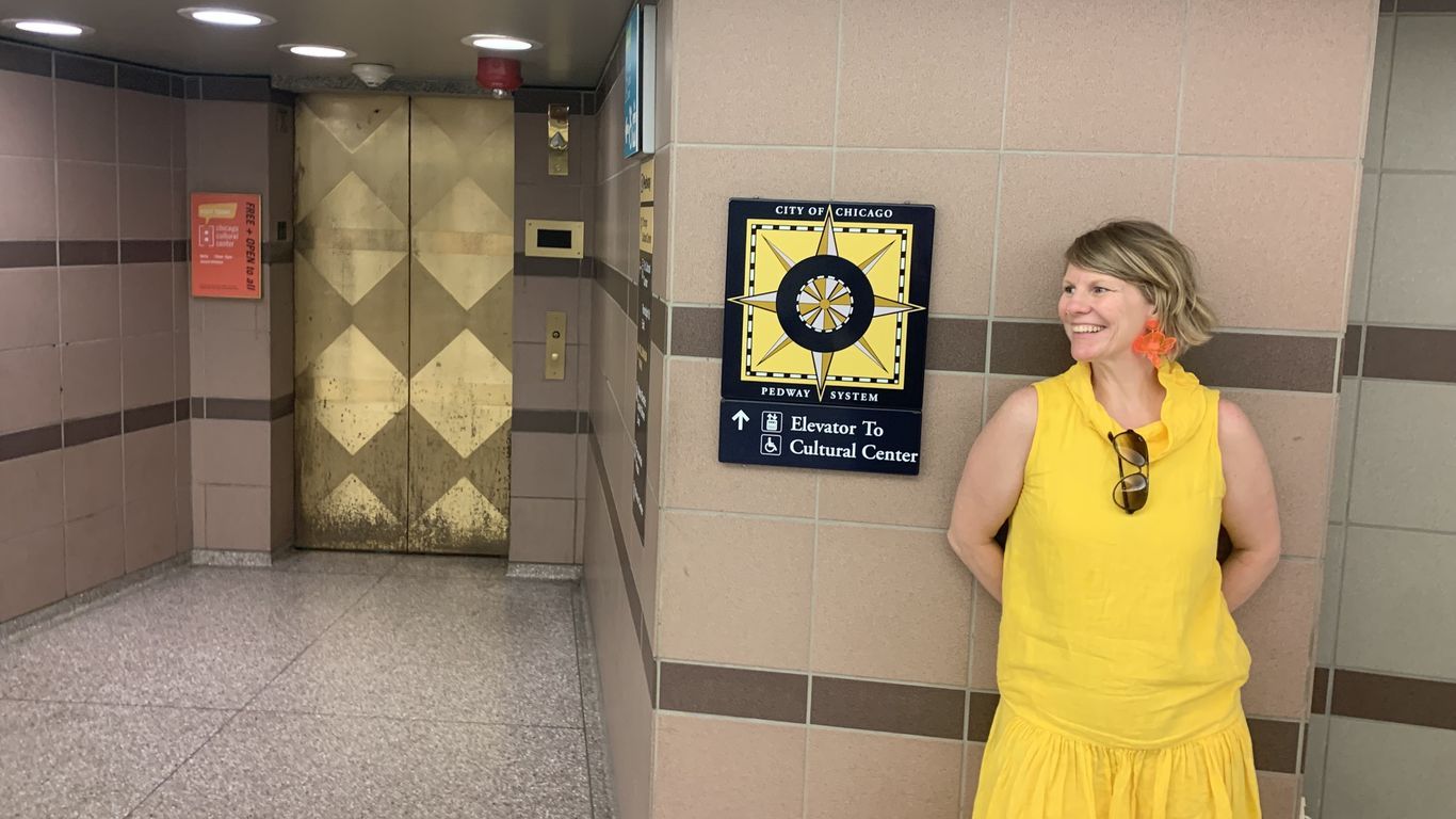 Carrie smiles by a Pedway sign, wearing a bright yellow dress.