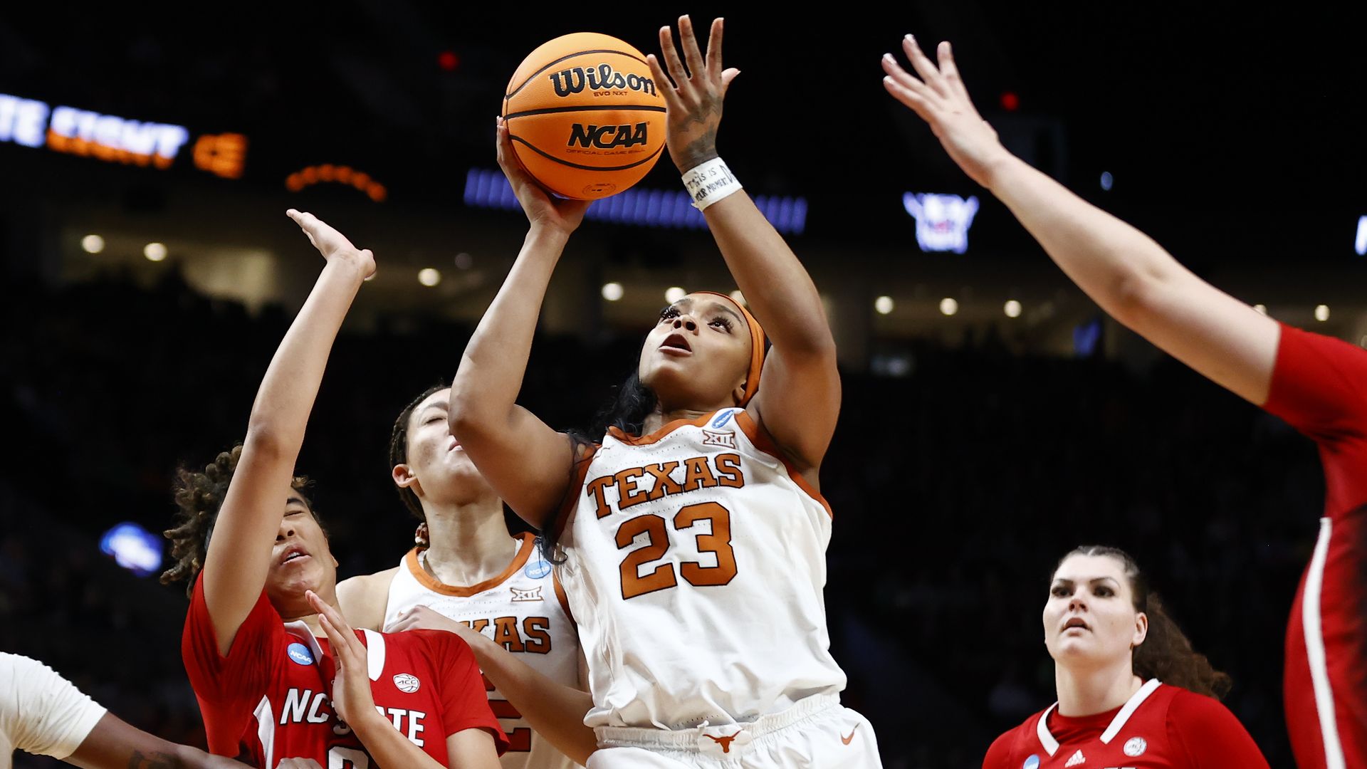 A photo of UT's Aaliyah Moore shooting a basketball as other players try to block her.