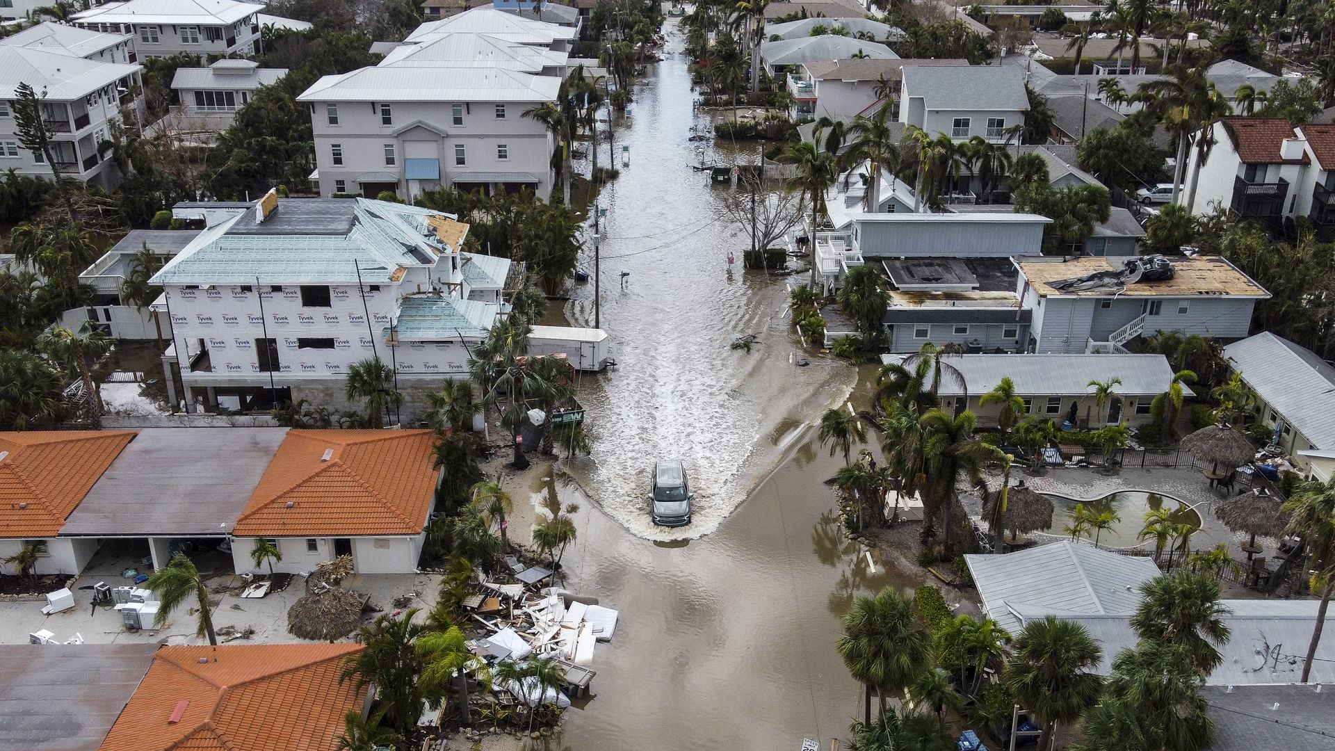 TOPSHOT - In this aerial photo, a vehicle drives though a flooded street after Hurricane Milton, in Siesta Key, Florida, on October 10, 2024. At least 10 people were dead after Hurricane Milton smashed into Florida, US authorities said October 10, 2024, after the monster weather system sent tornados