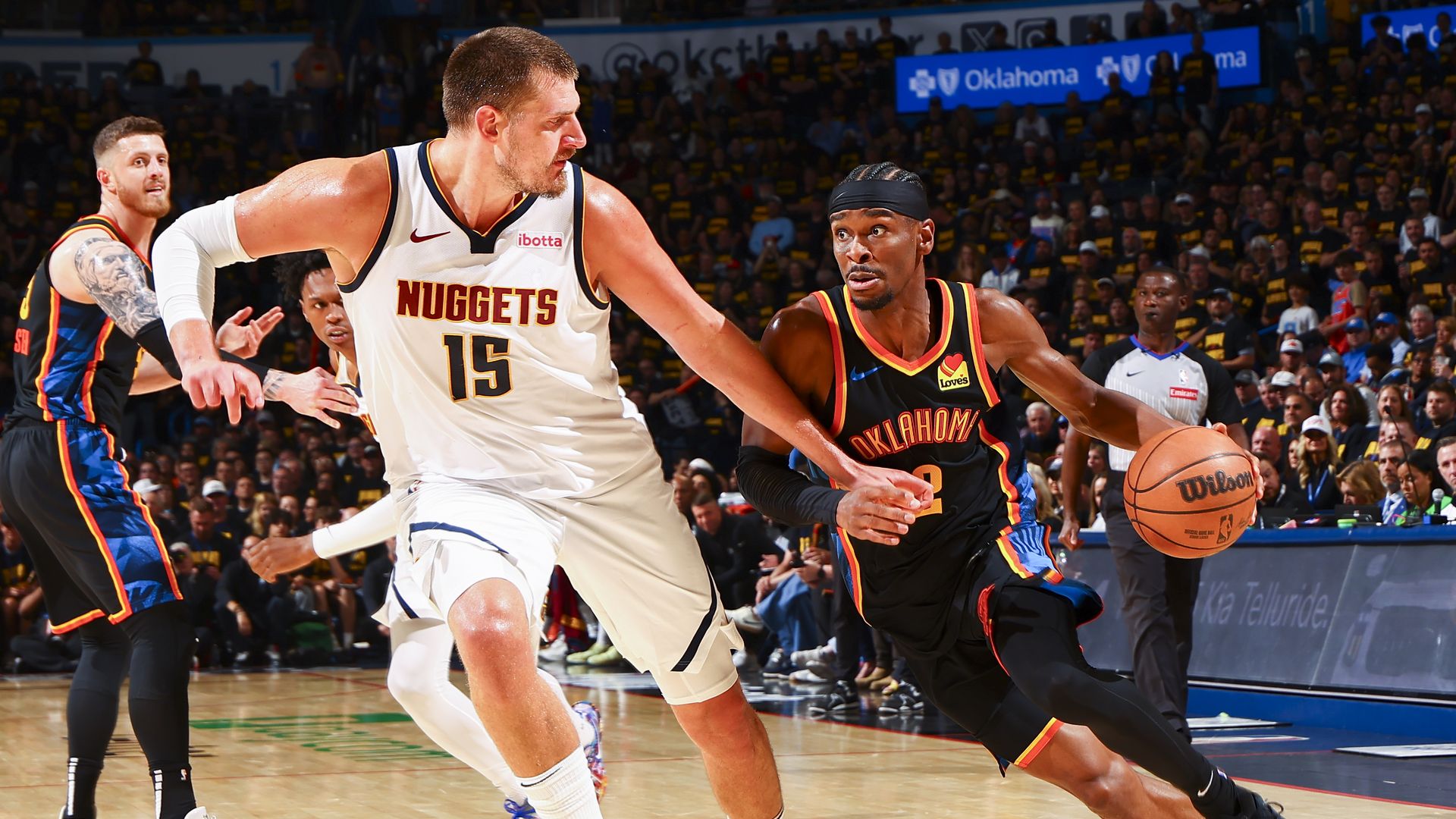 Two men playing basketball, with one man handling a ball while moving forward. 