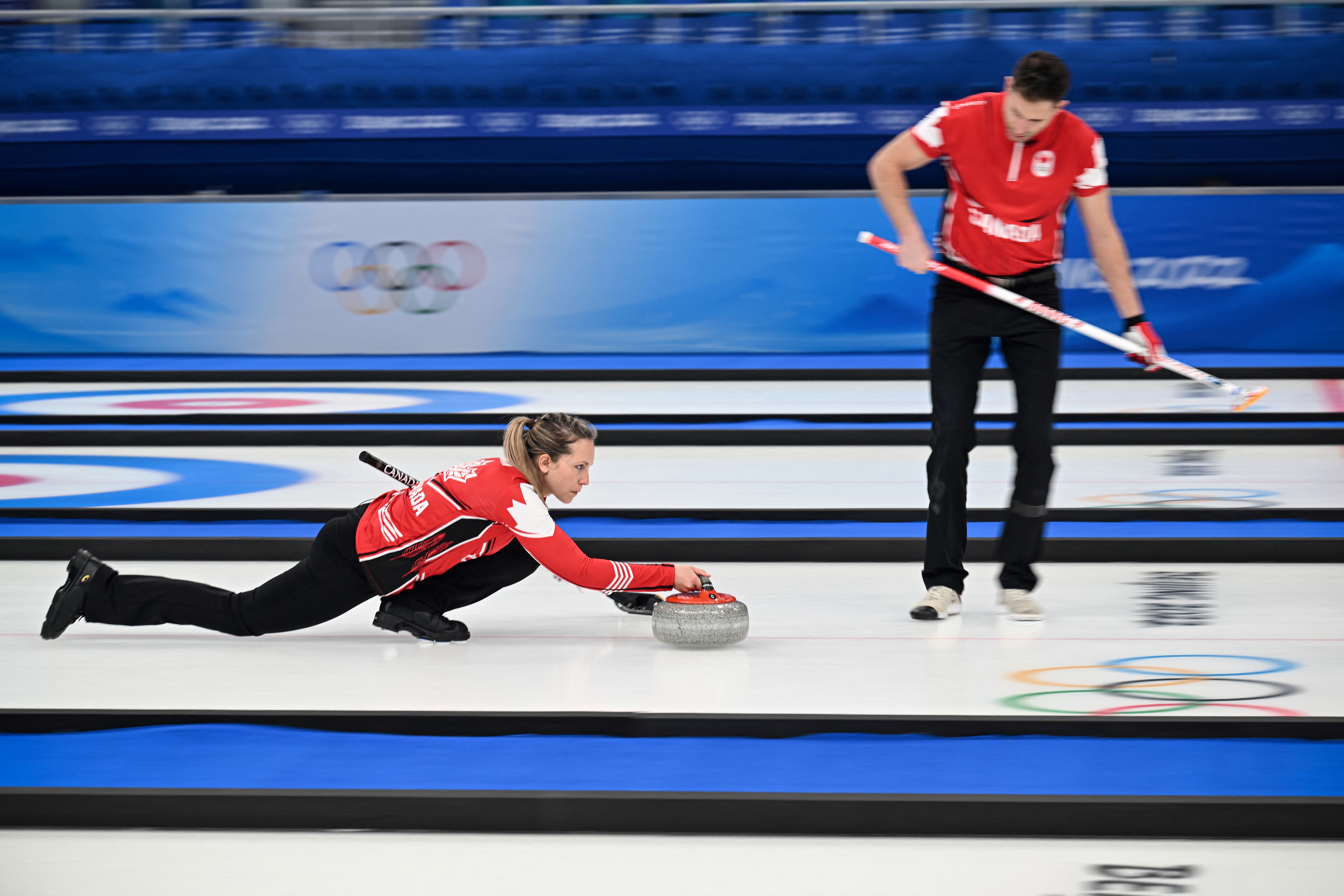 Canada's Rachel Homan (L) curls the stone during the mixed doubles round robin session 5 game of the Beijing 2022 Winter Olympic Games curling game against Switzerland February 4