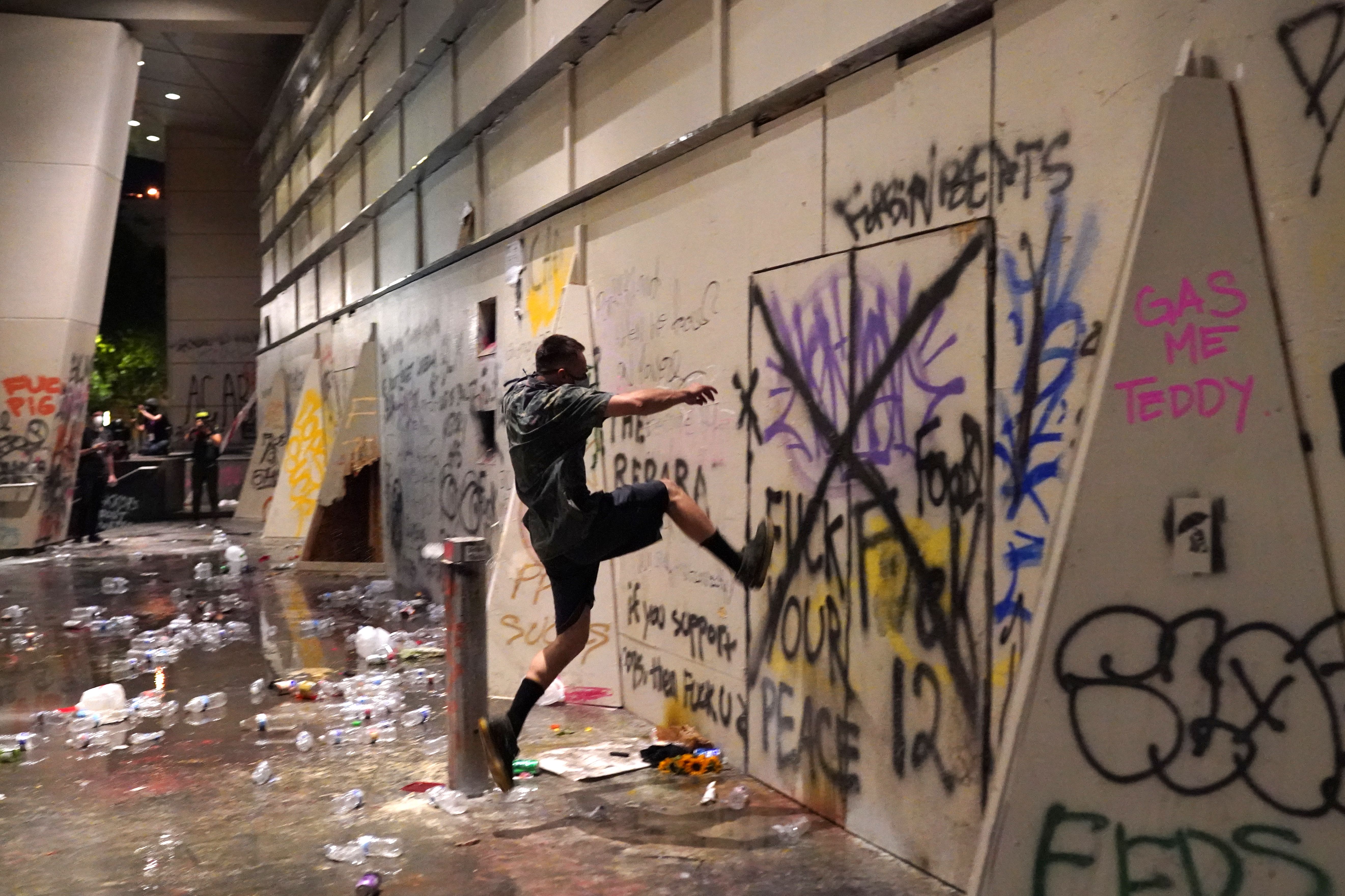 A protester kicks a wall covered in graffitti 