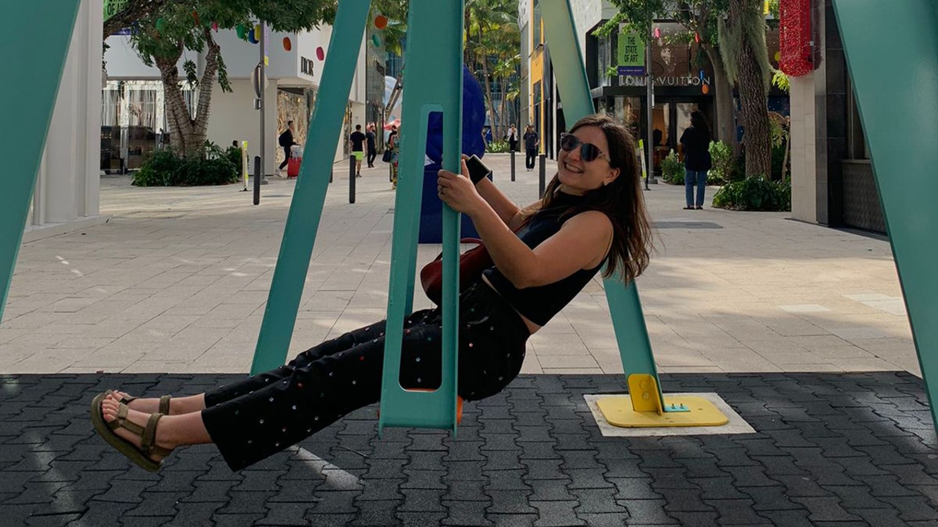 Kady Murzin swings on a giant swing while wearing sunglasses