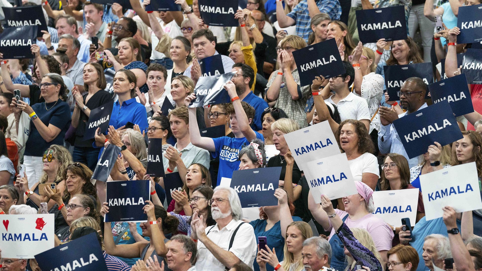 Supporters hold up "Kamala" signs during a rally at West Allis Central High School near Milwaukee yesterday.