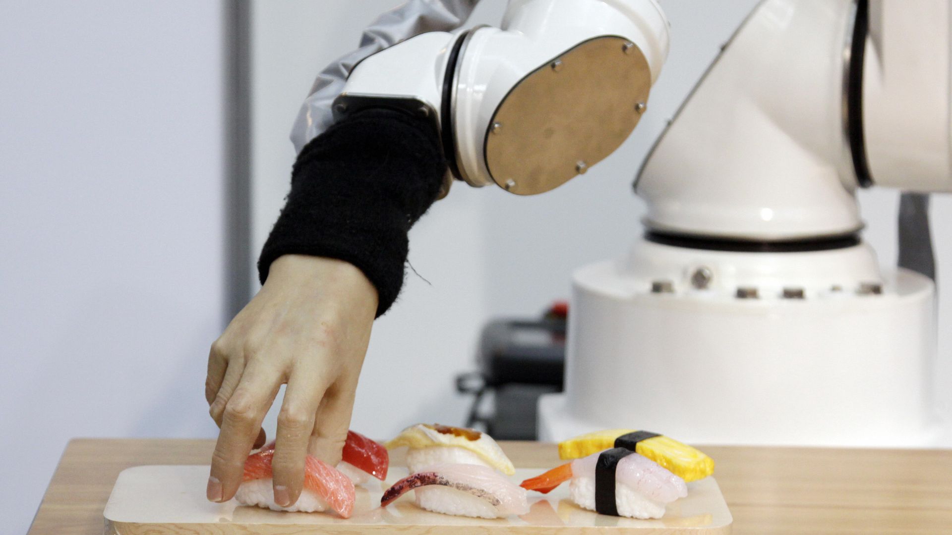 A robotic hand picks up sushi