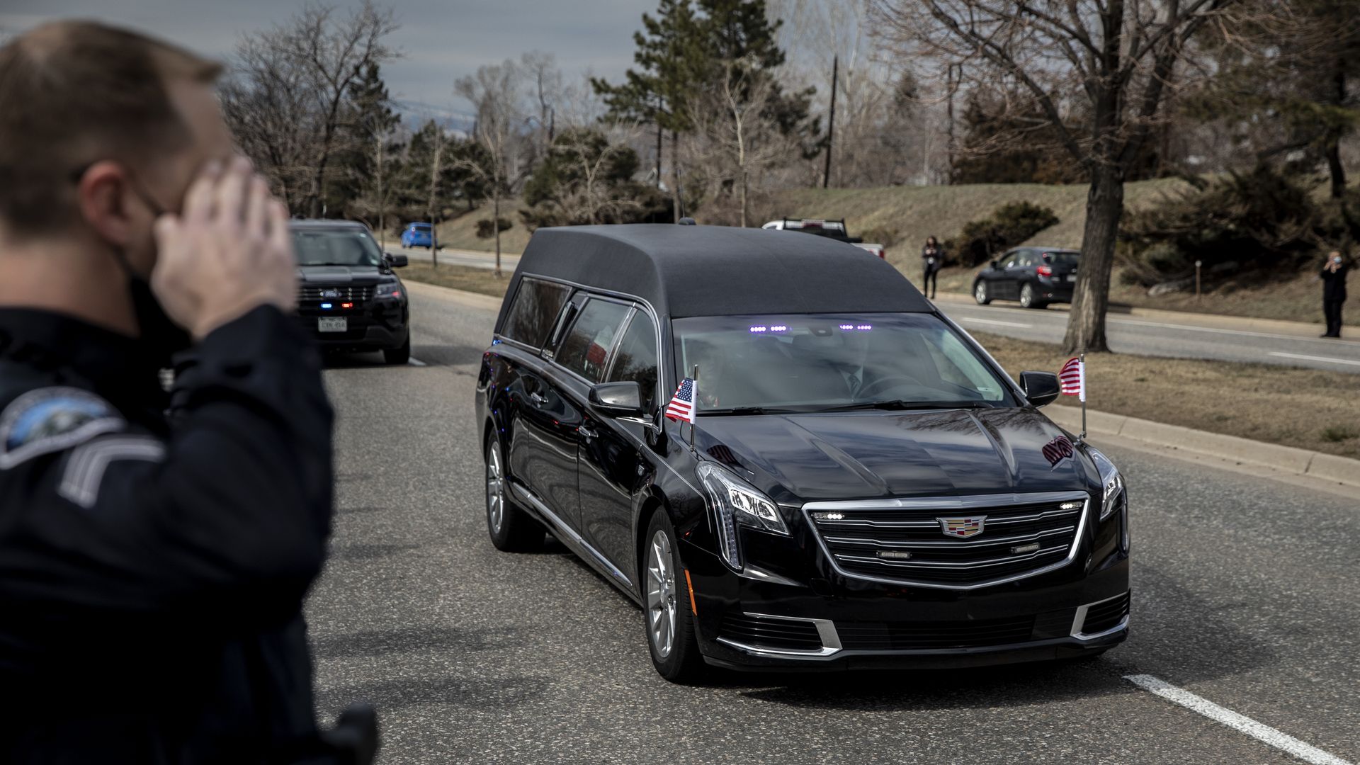 A police officer is seen saluting the hearse carrying the body of slain Boulder Police Officer Eric Talley.