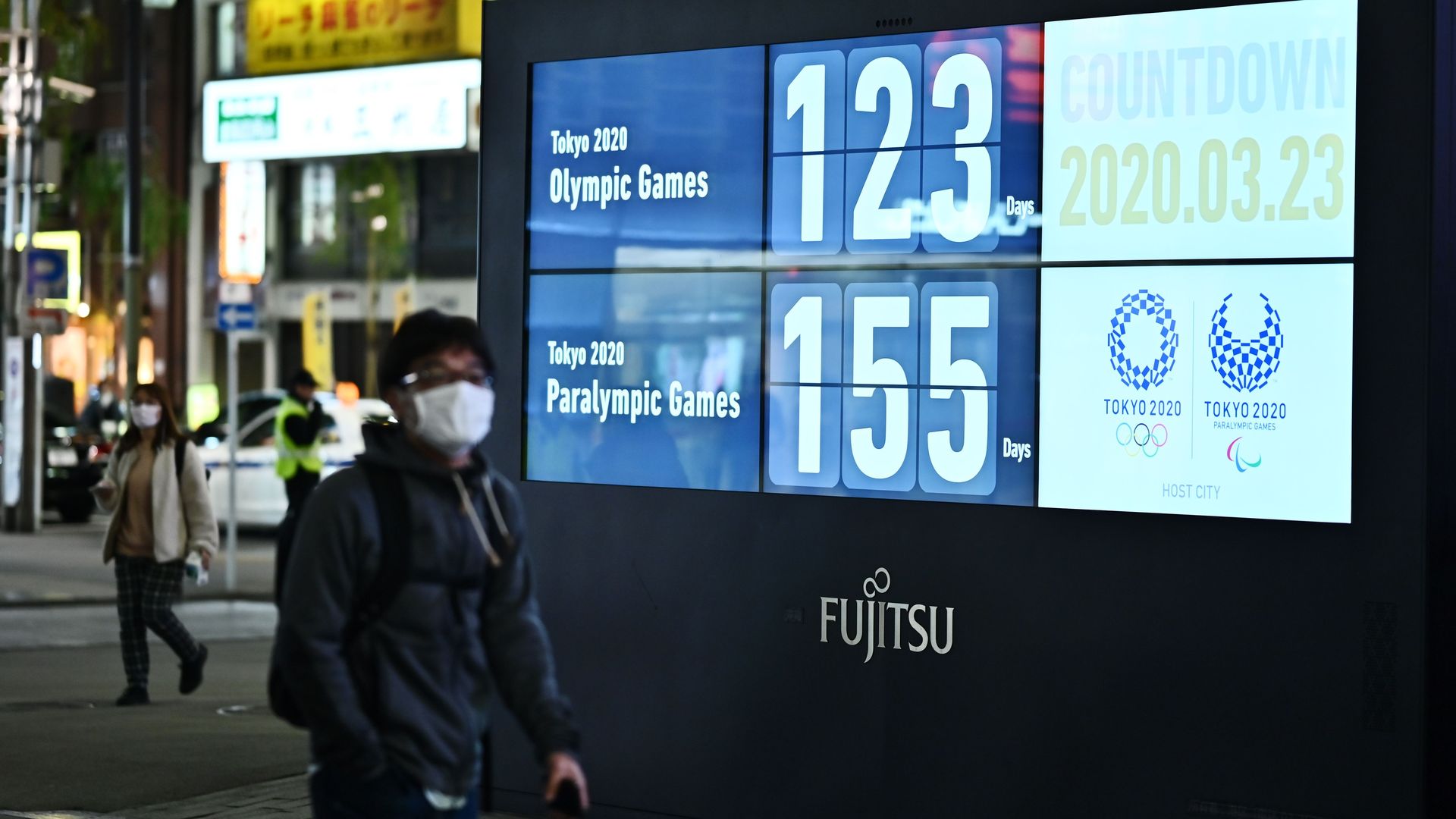 A man wearing a face mask, amid concerns of the COVID-19 coronavirus, walks past a display showing a countdown to the start of the Tokyo 2020 Olympic Games in Tokyo 