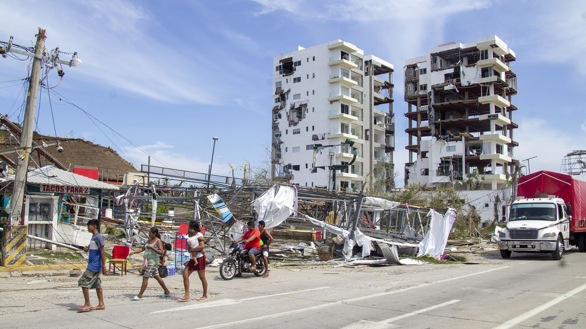 People walk on a street amid storm damage in Acapulco, Mexico after Hurricane Otis.