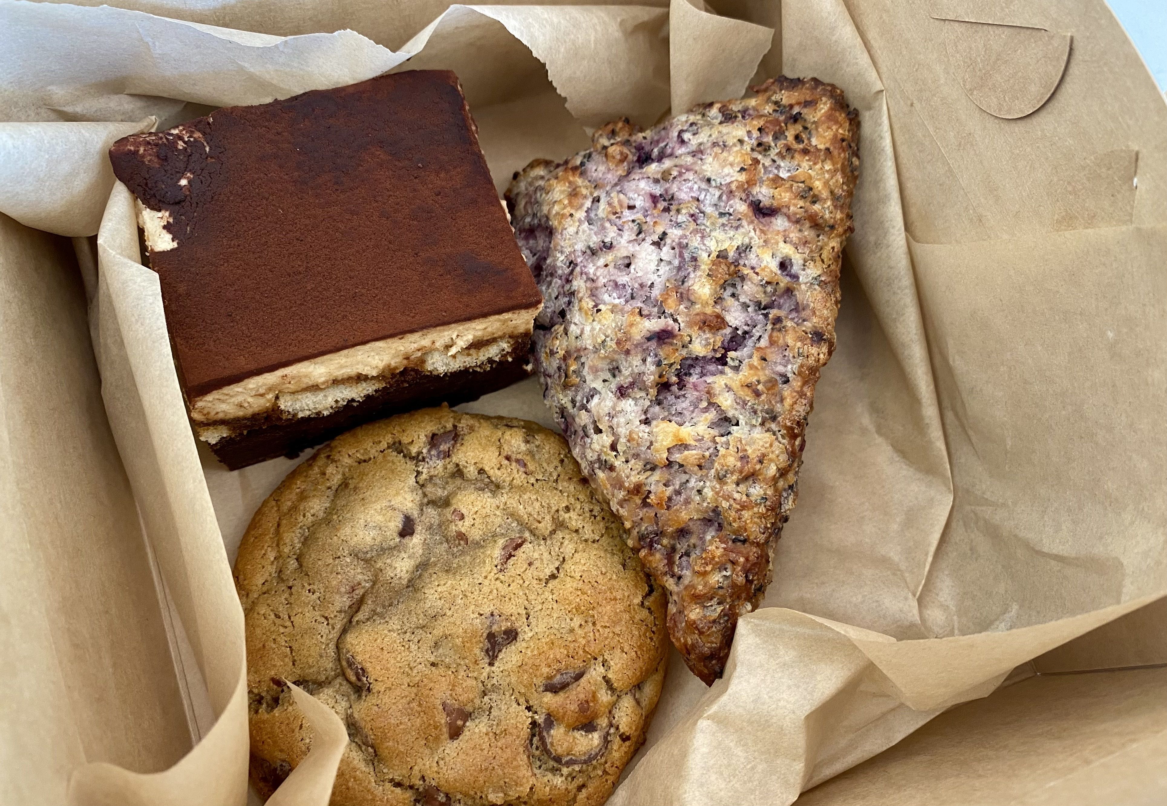 Photo of three baked goods in a box: a scone, cookie and tiramisu 