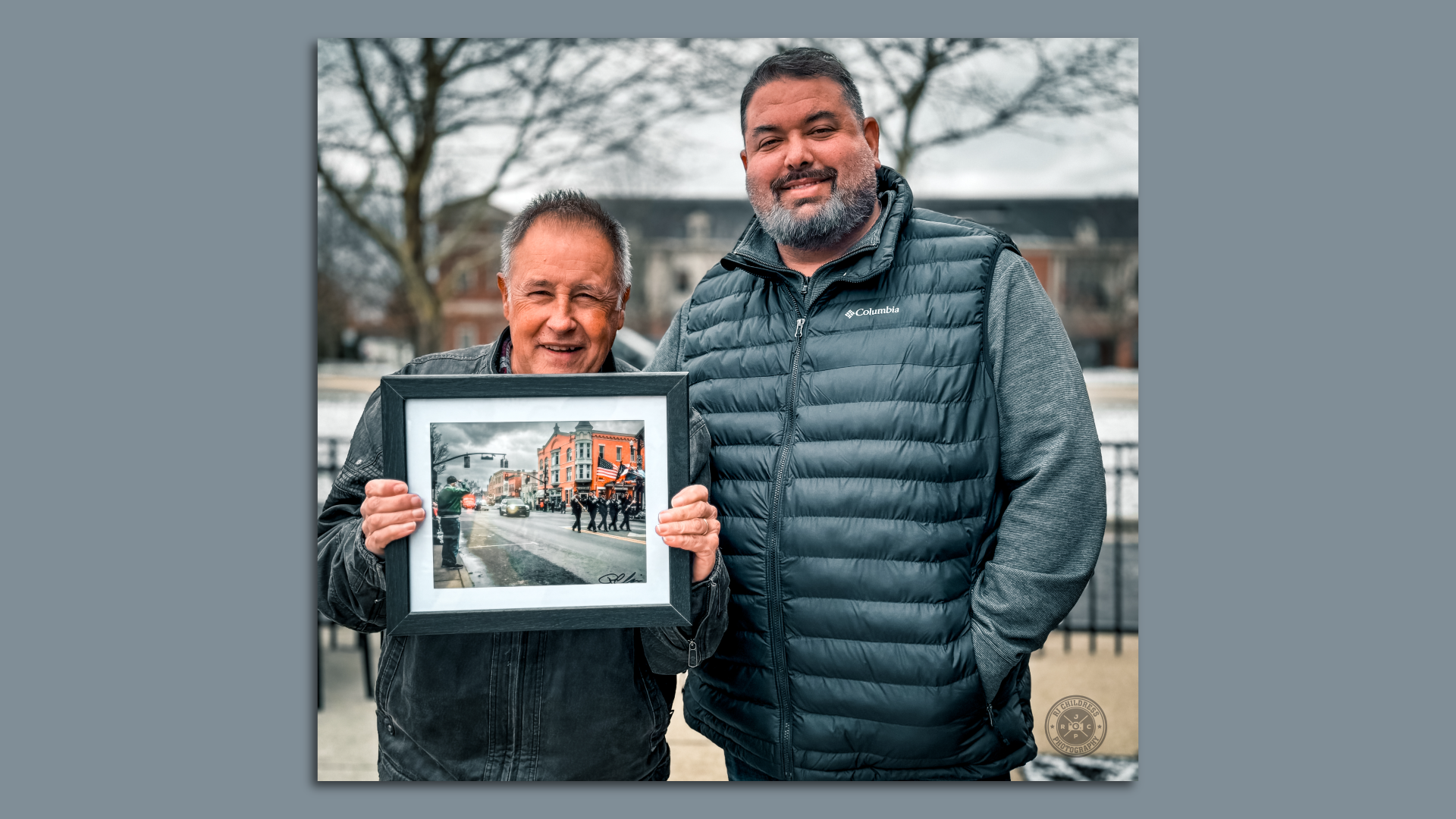 Photographer Ryan J. Childress stands next to a man he photographed as he holds the picture of himself