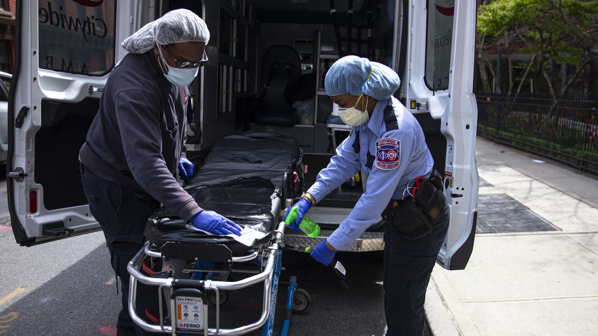Two emergency medical staff of a private ambulance company sanitize a hospital gurney 