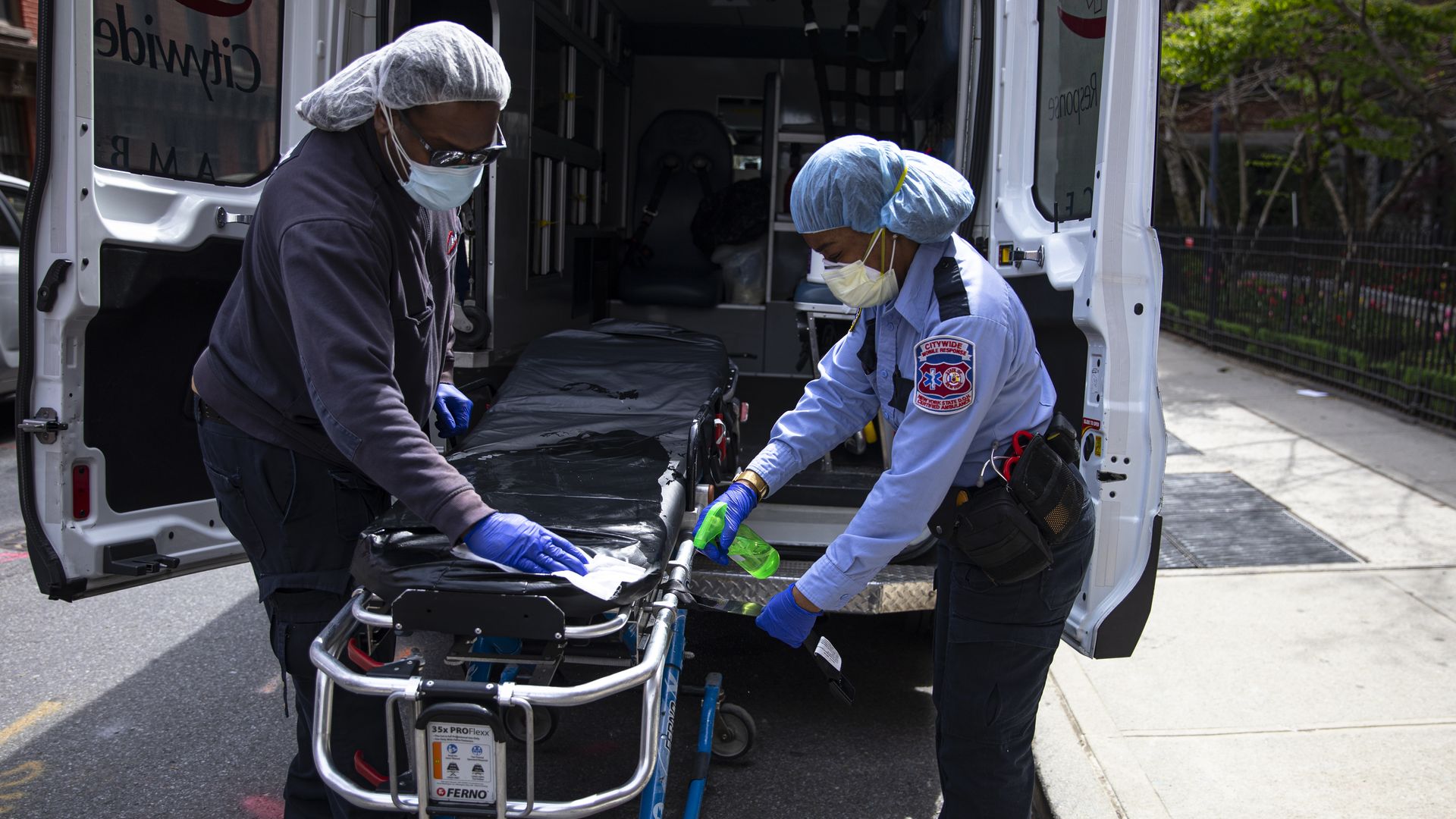 Two emergency medical staff of a private ambulance company sanitize a hospital gurney