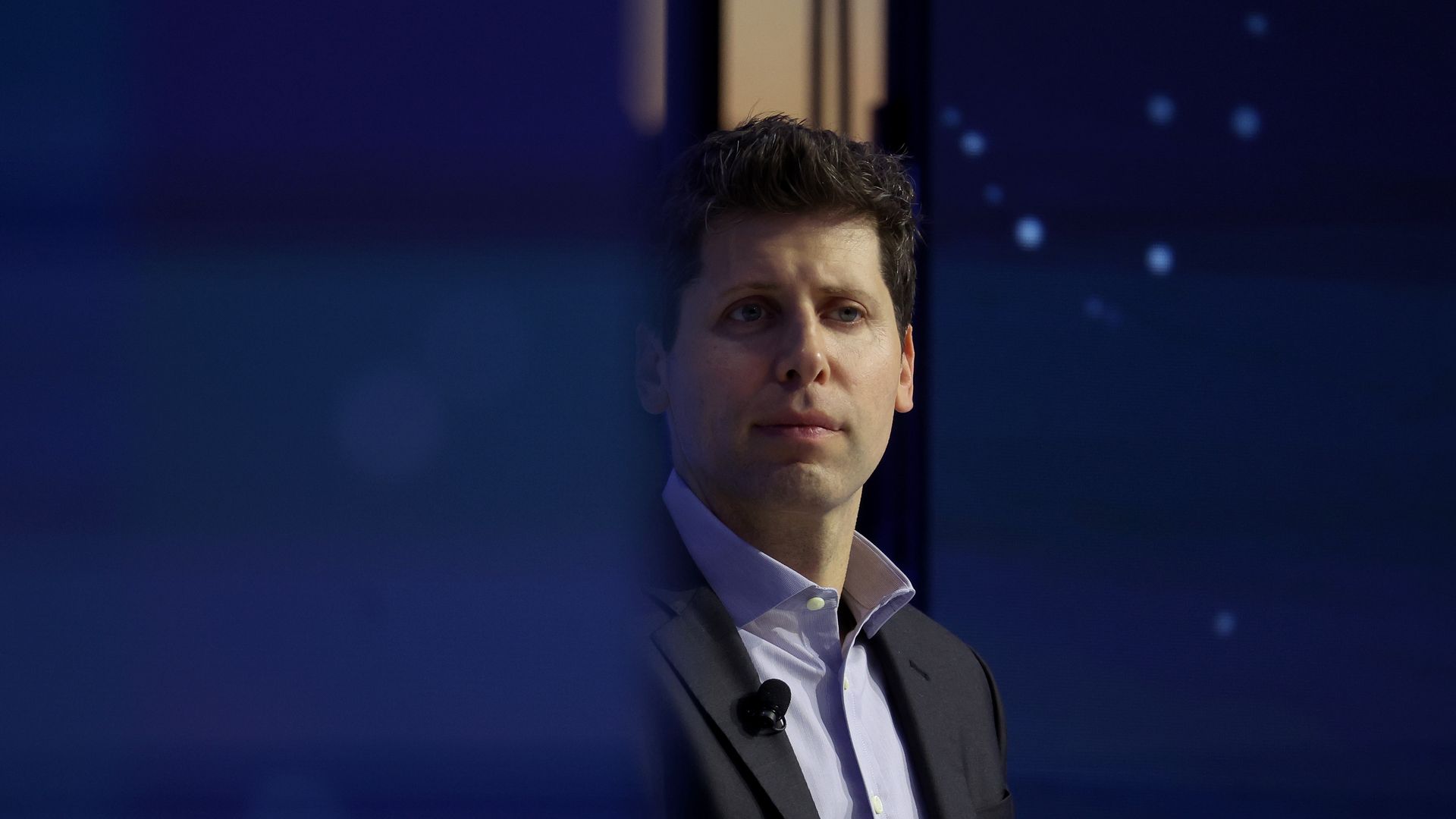 Sam Altman, in a suit and open-collared shirt.