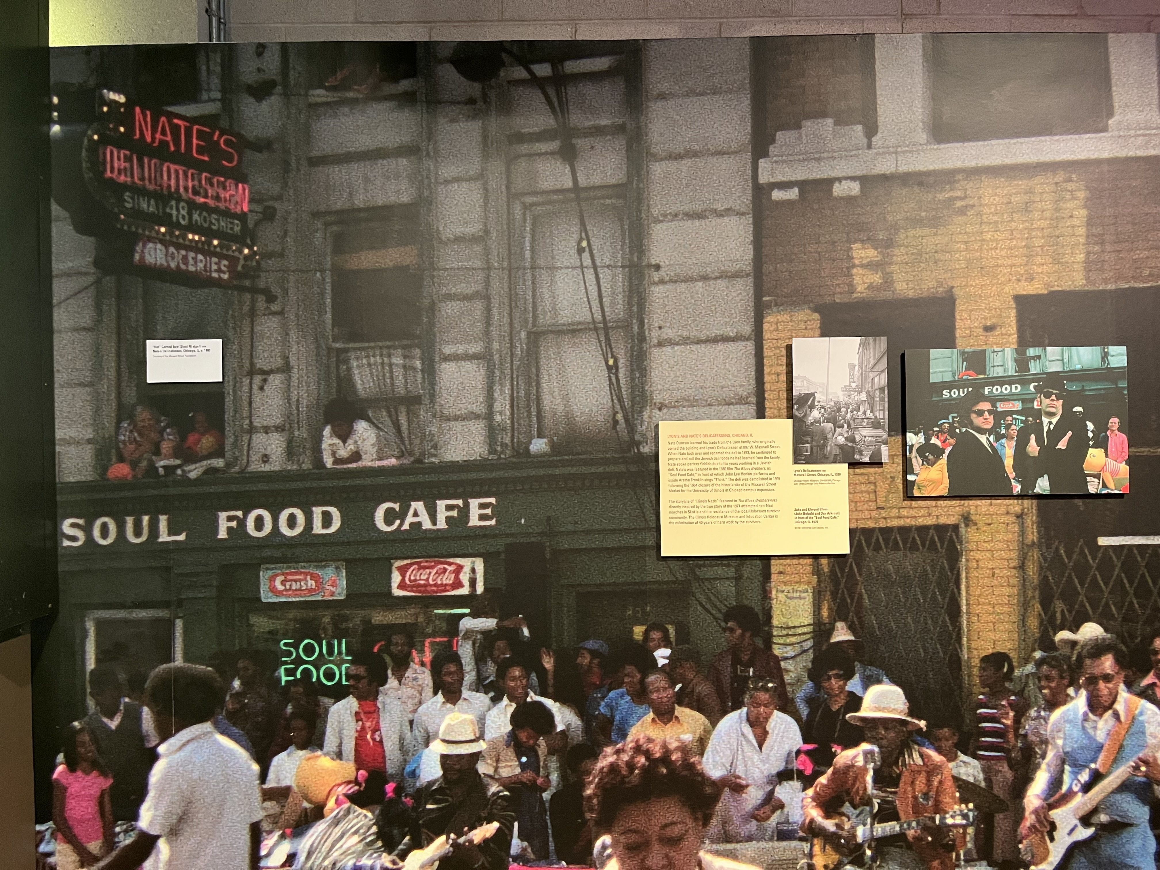 Storefront of Soul Food Cafe with people in front and a photo of the Blues Brothers.