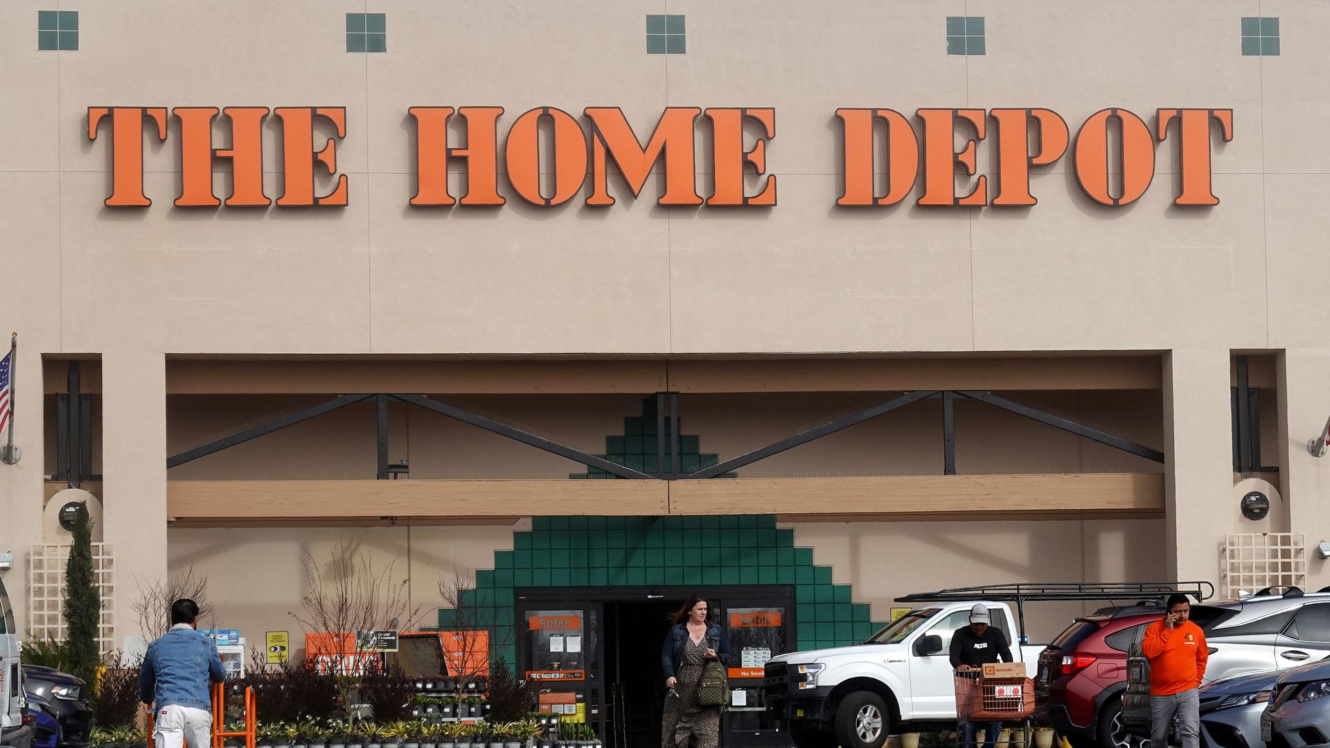 Home Depot store front with shoppers pushing cart into the store from the parking lot