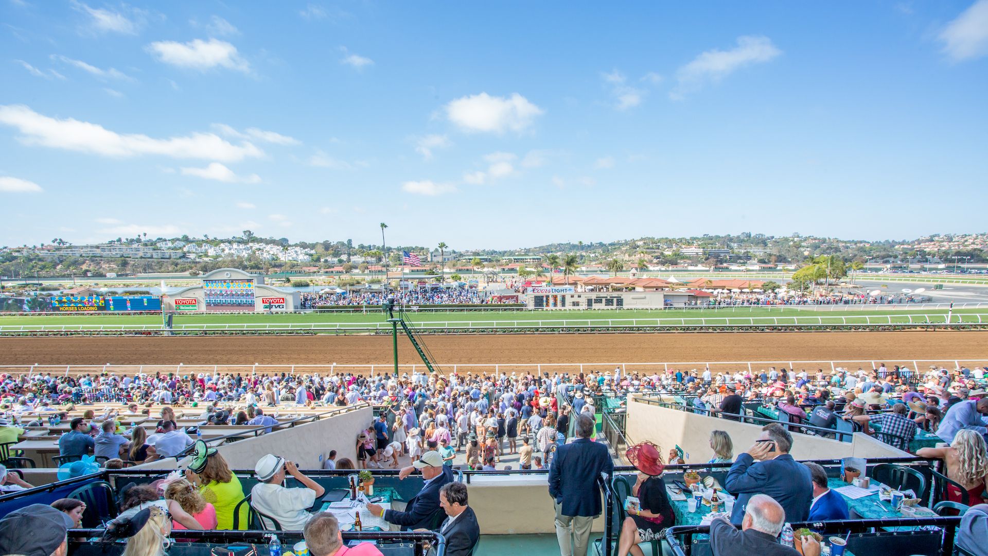 People dressed up for horse races sit trackside at the Del Mar Thoroughbred Club. 