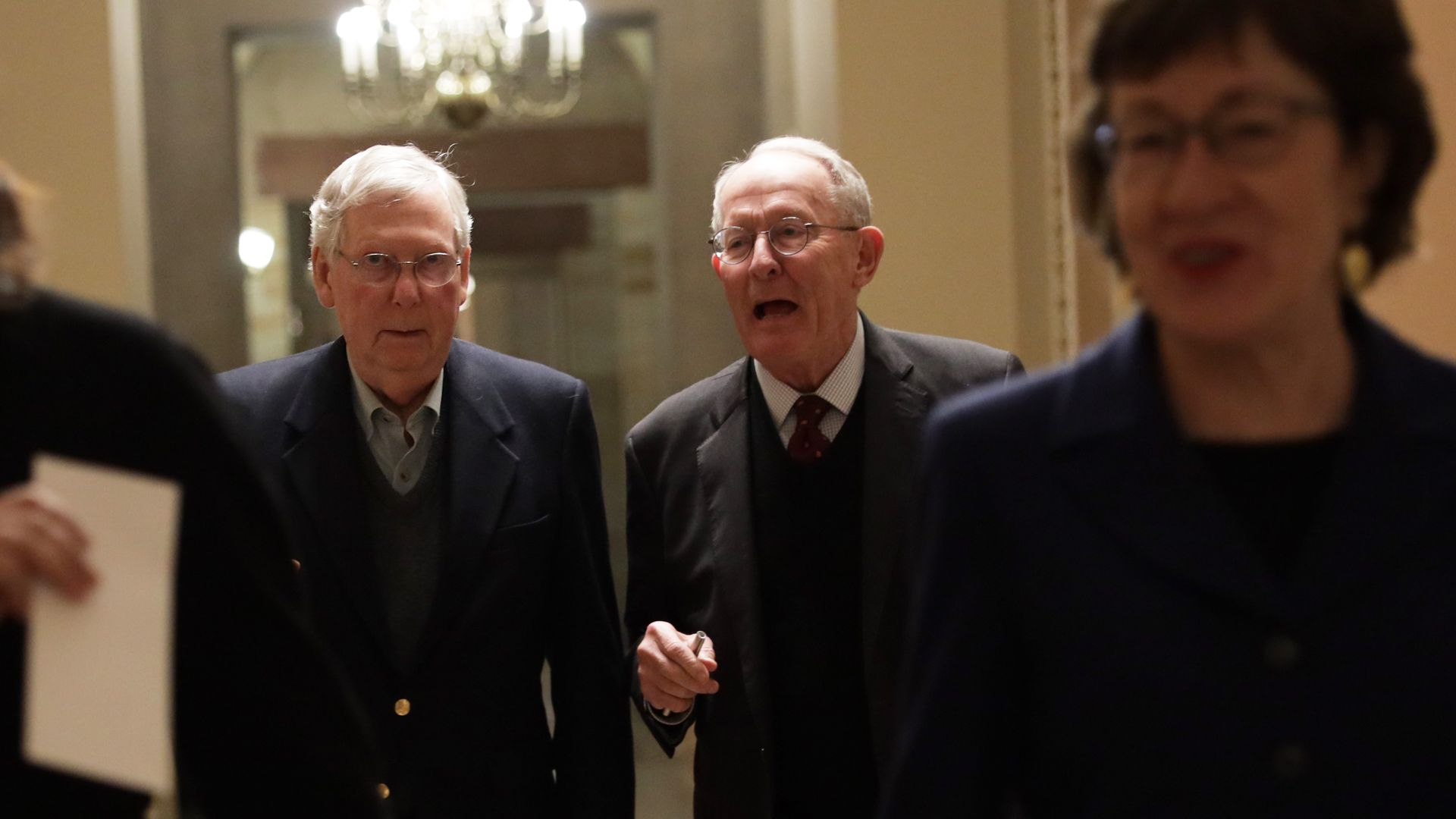 Senator Susan Collins walks down a hall while Majority Leader Mitch McConnell and Senator Lamar Alexander walk together behind her.