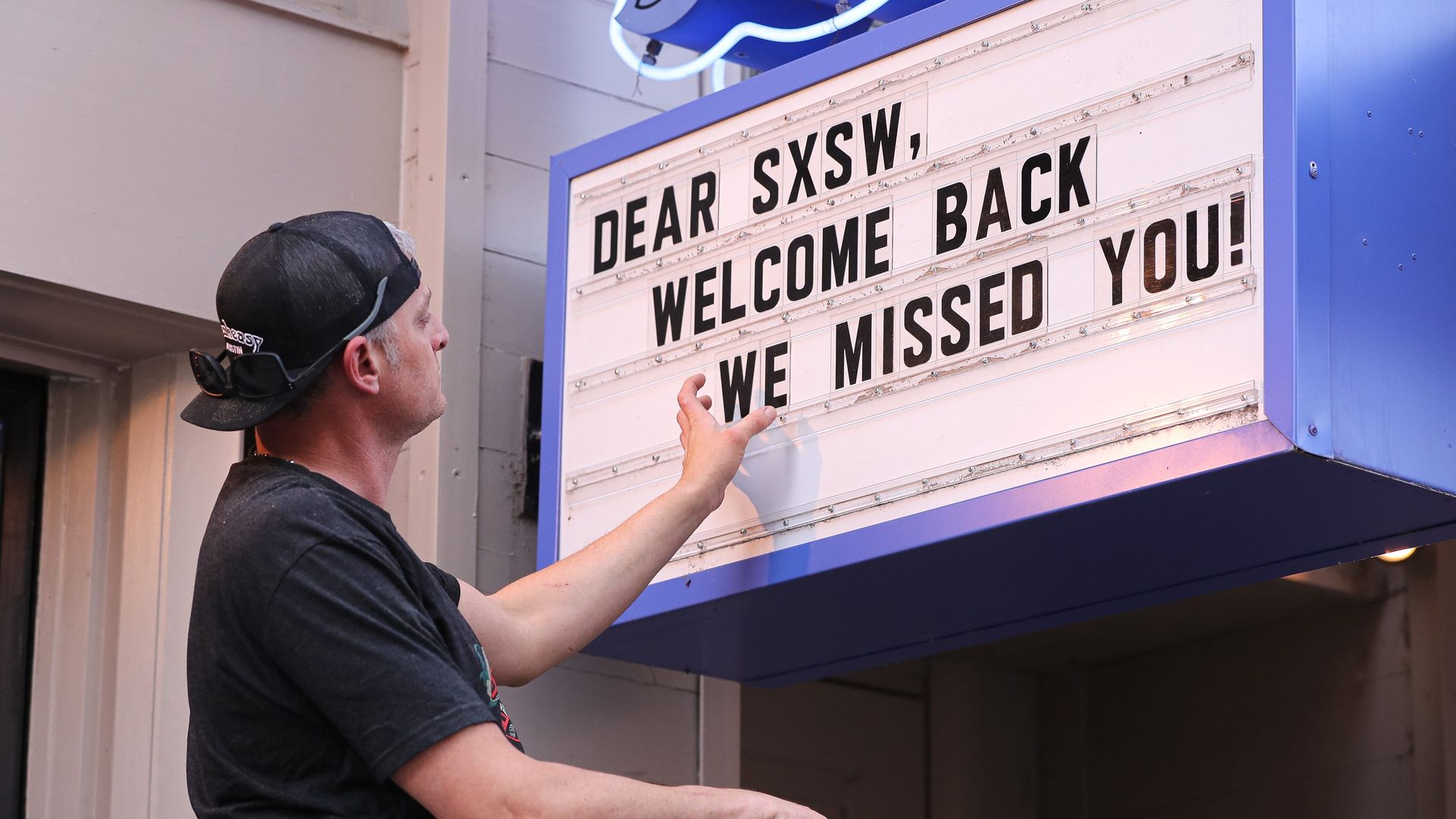A person puts up a welcome back SXSW sign