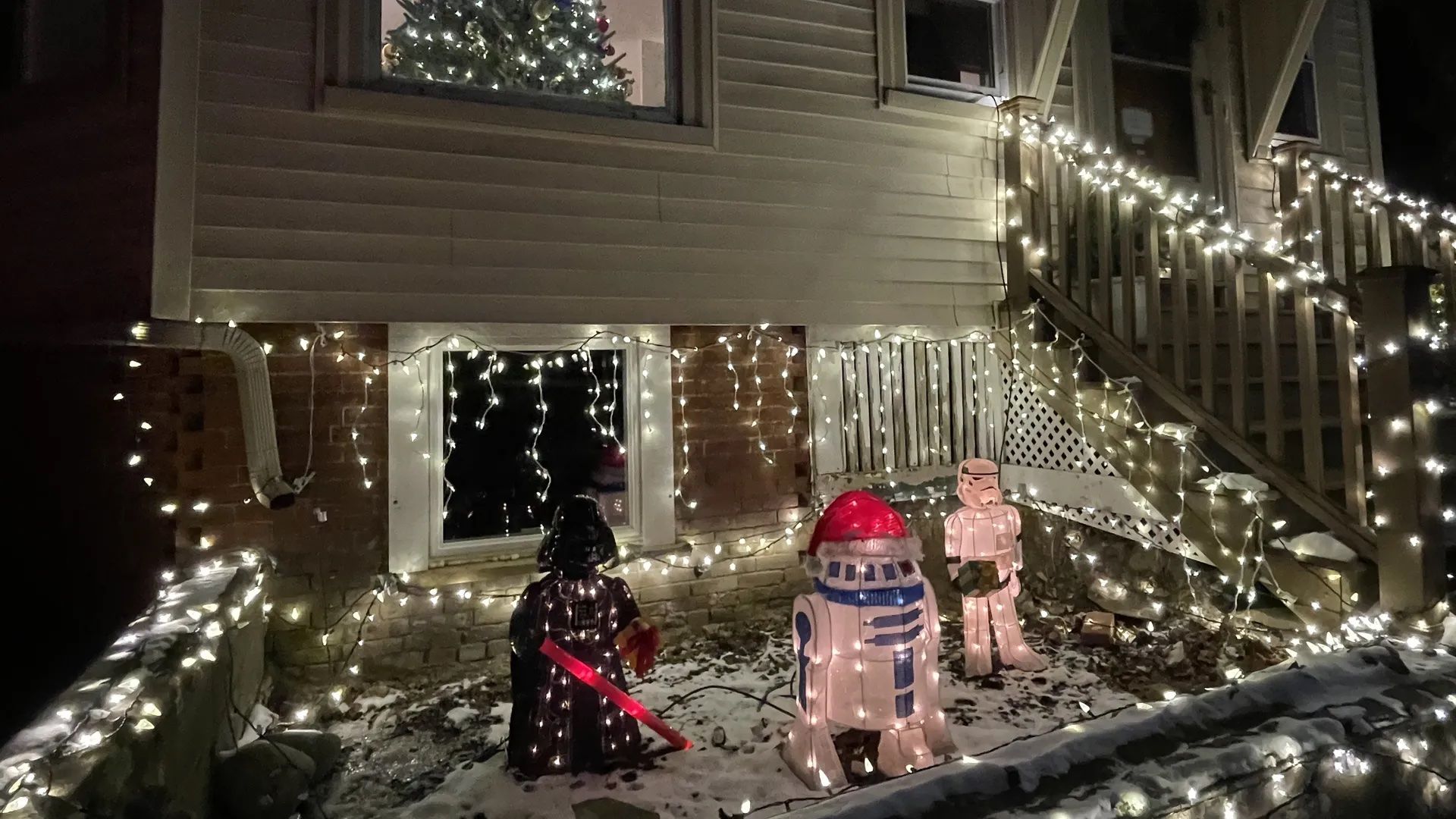 A holiday installation outside a Somerville house showing R2D2 with a Santa hat, Darth Vader and a storm trooper.