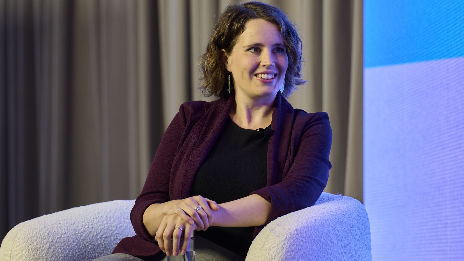 Helen Toner seated on stage wearing a burgundy jacket