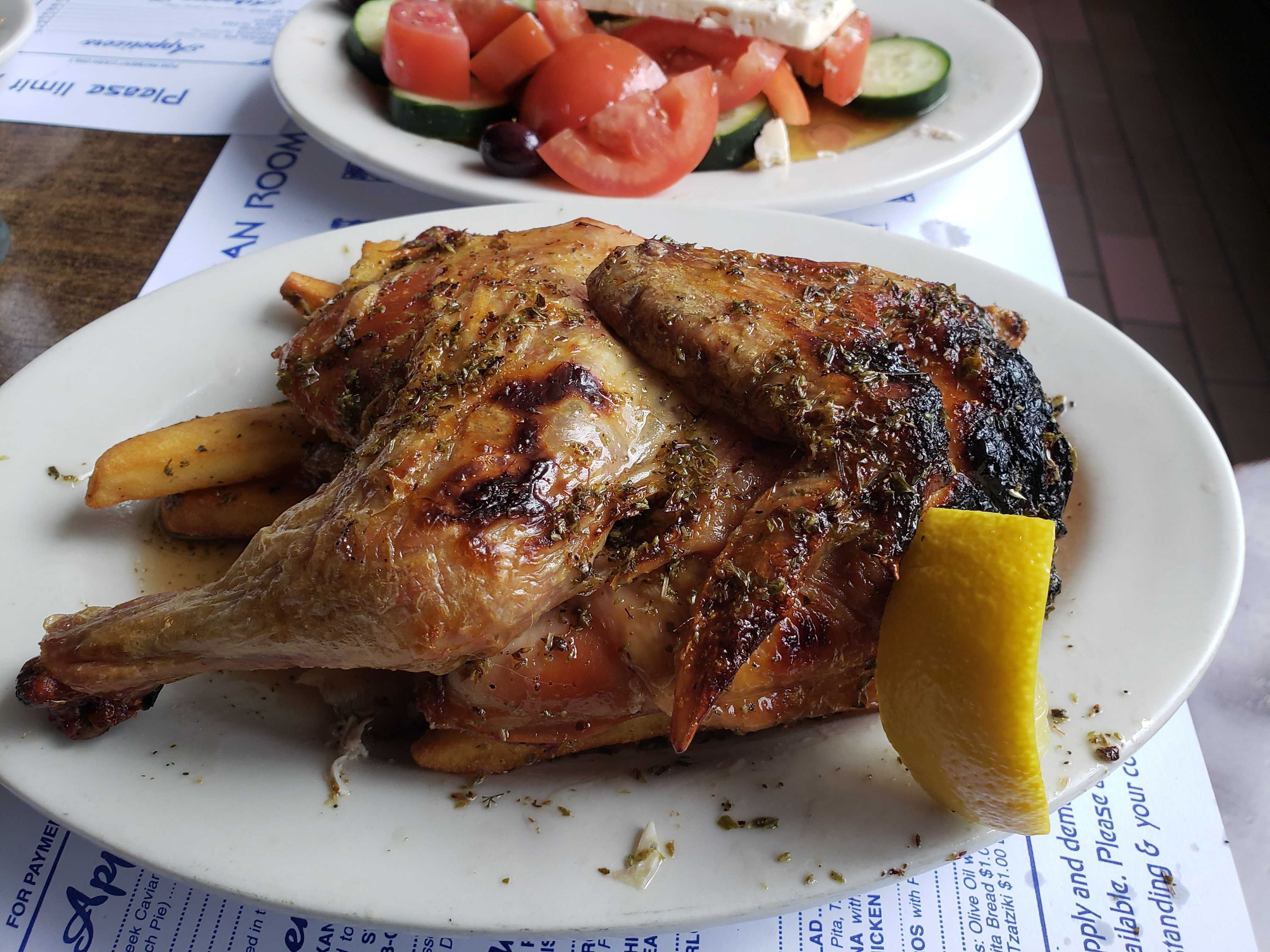 Photo of a roasted chicken on a plate with lemon.