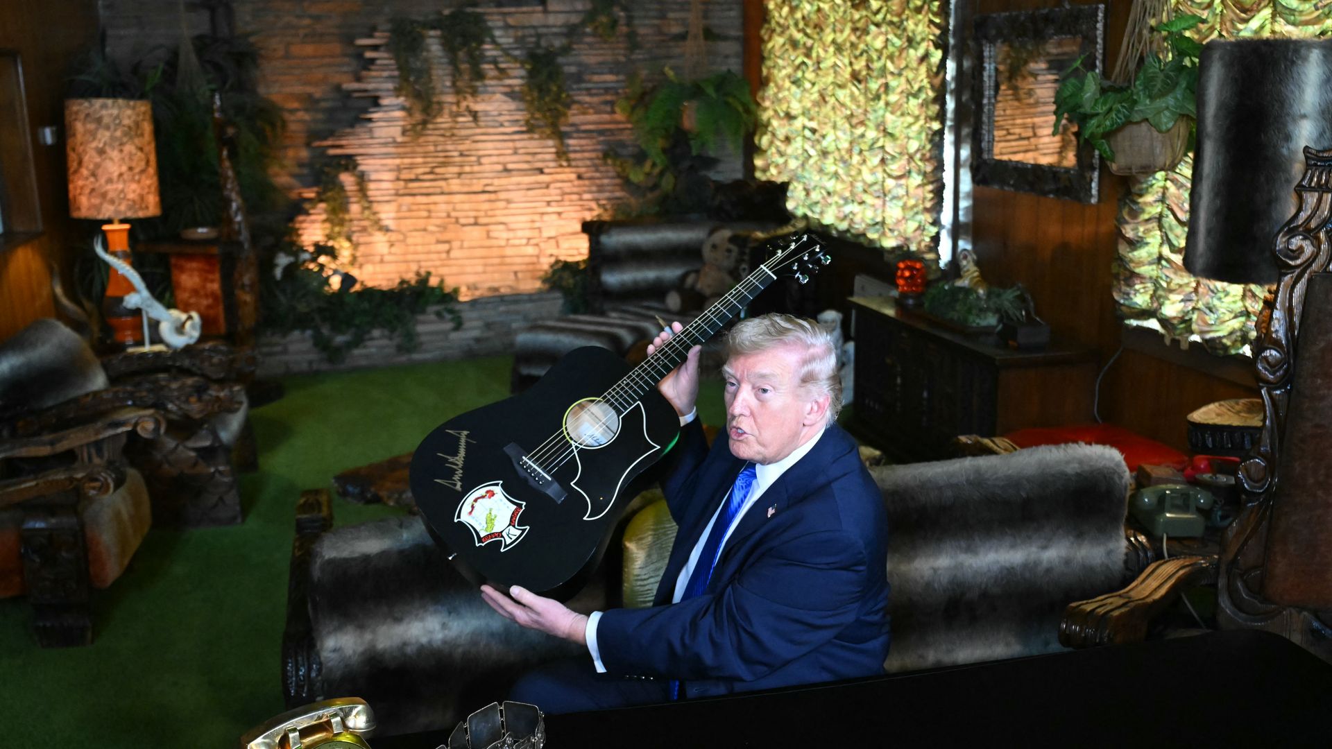US President Donald Trump shows a replica of one of Elvis Presley's guitars after he signed it, as he tours the Jungle Room during his visit to Graceland in Memphis, Tennessee