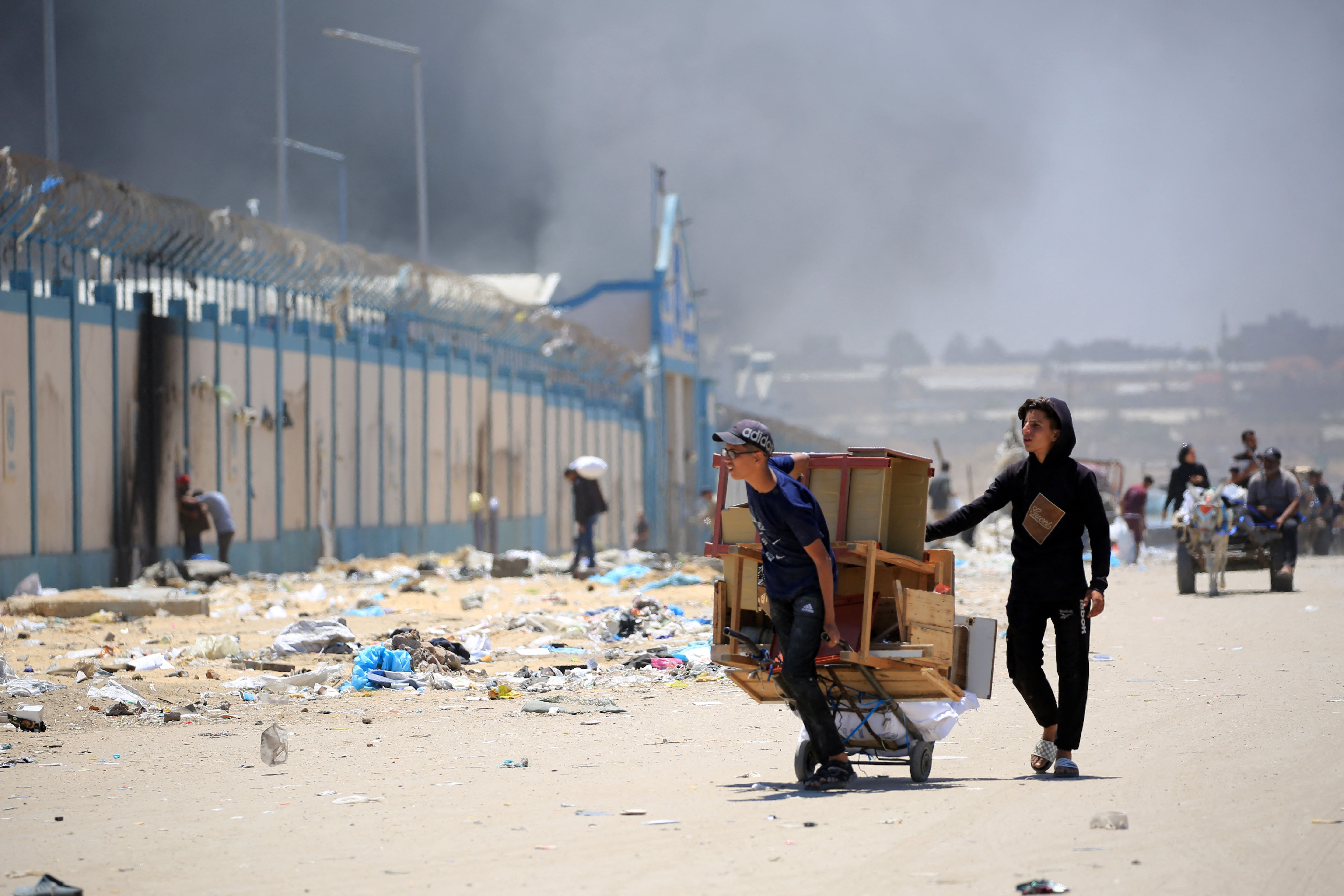 A person walks with a cart through a dusty street