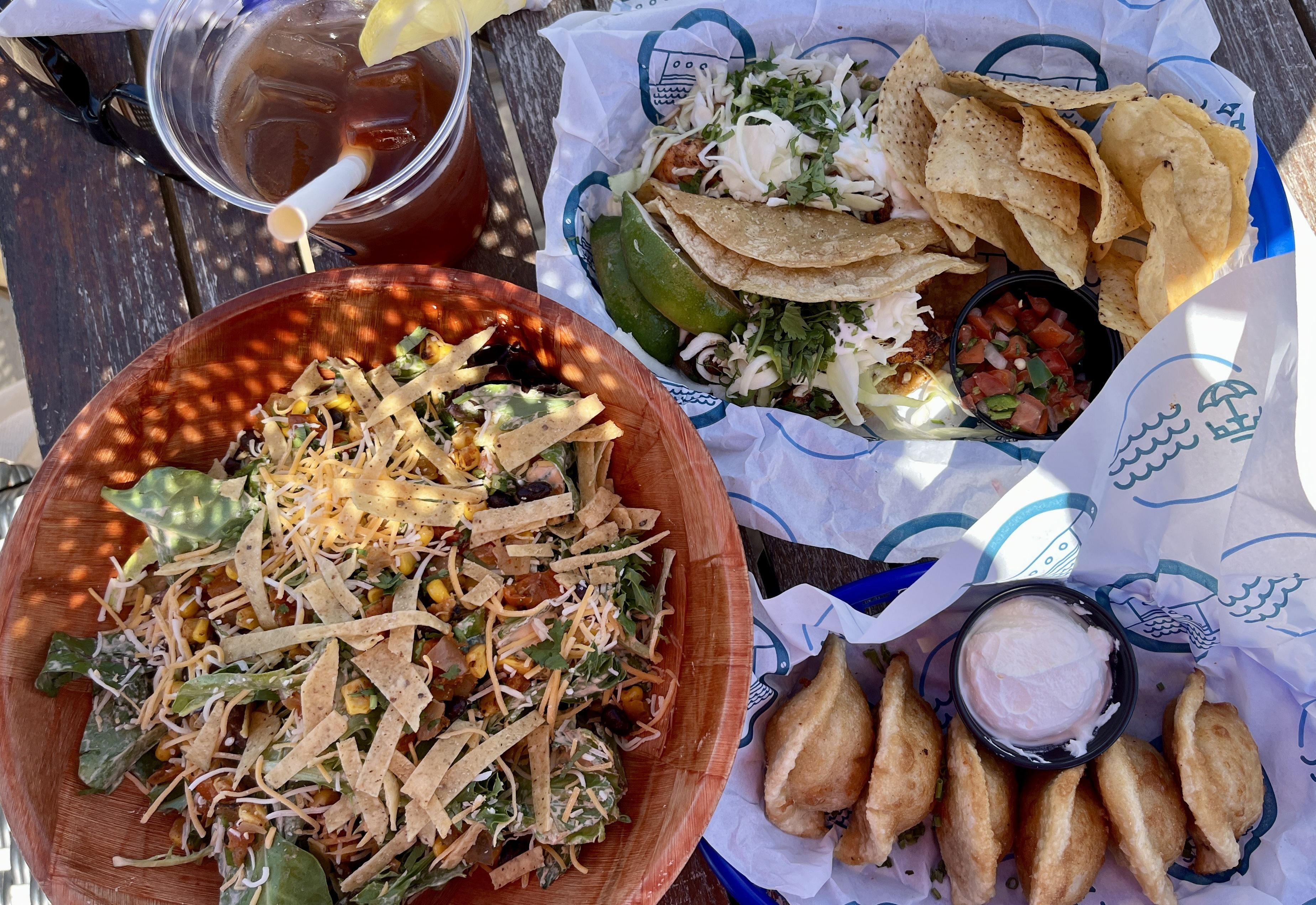 Photo of tacos and salads on a table outside 