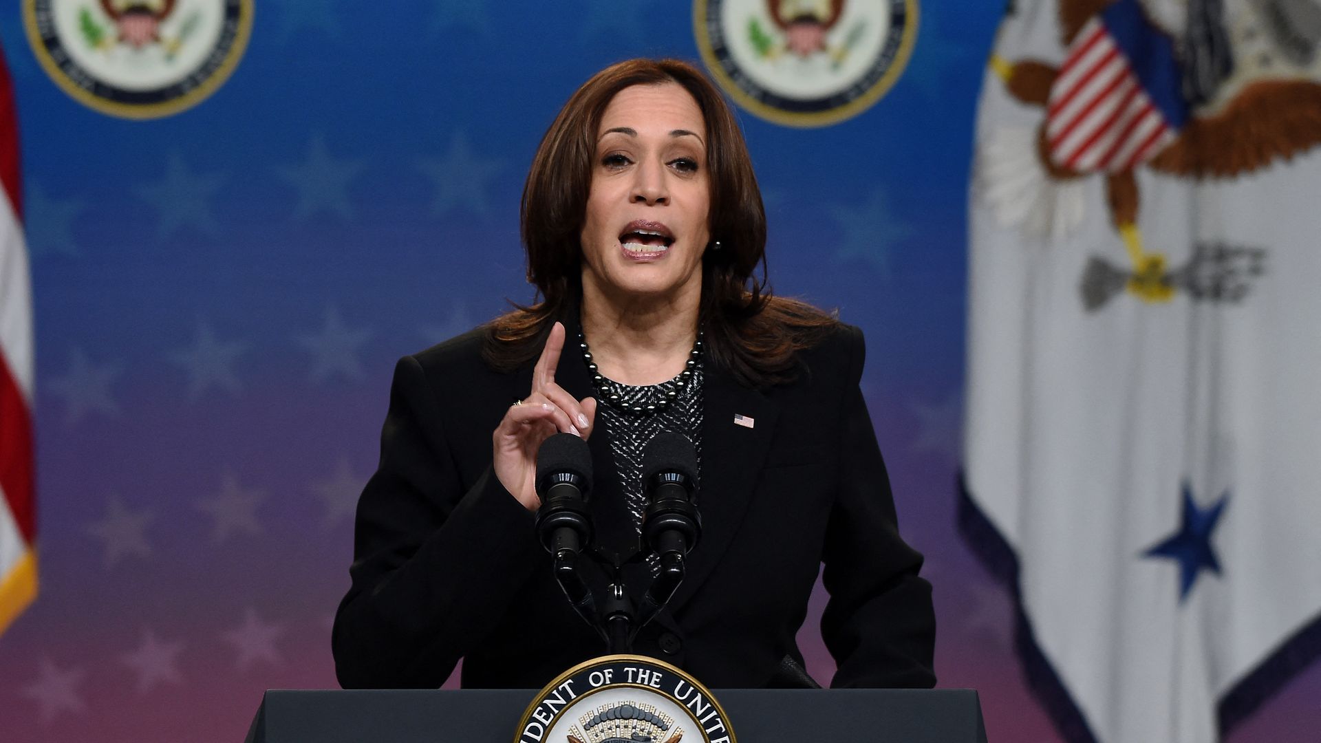Photo of Kamala Harris speaking and gesturing with her hand from behind a podium