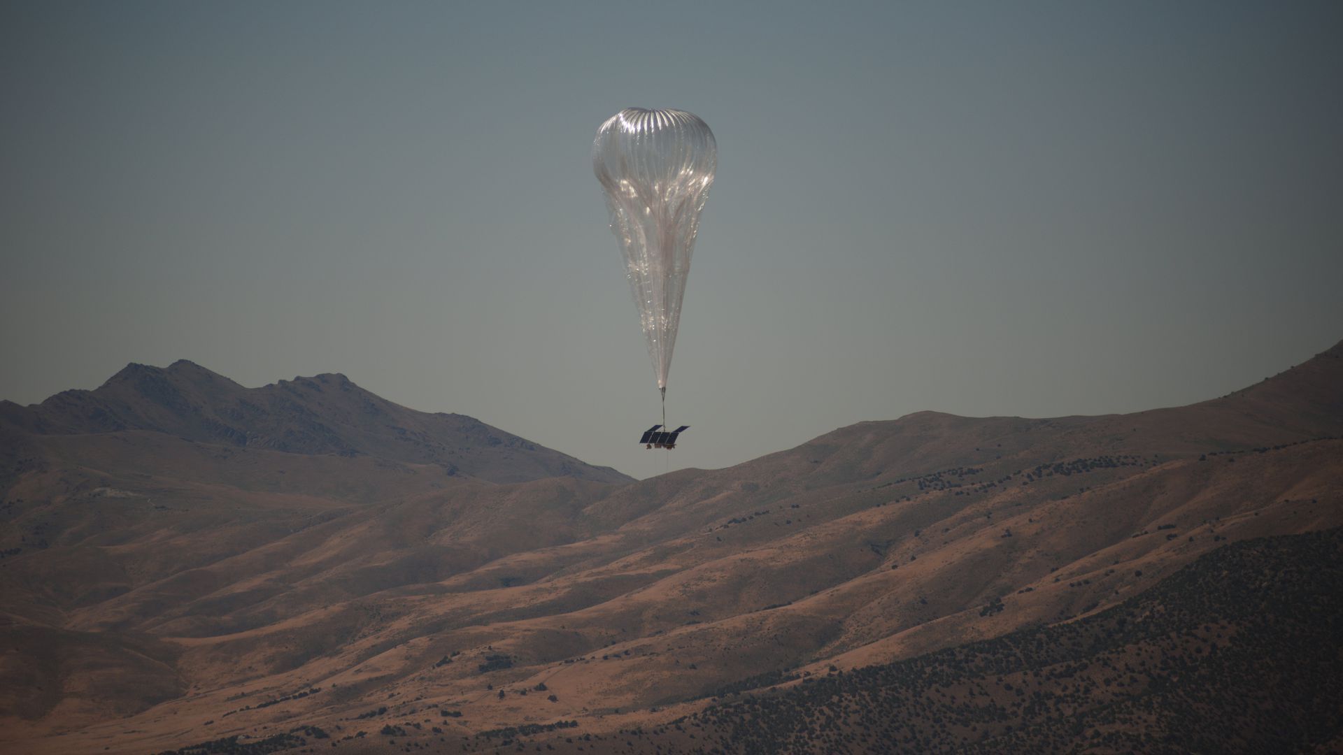 A Loon balloon flies over a mountain range 