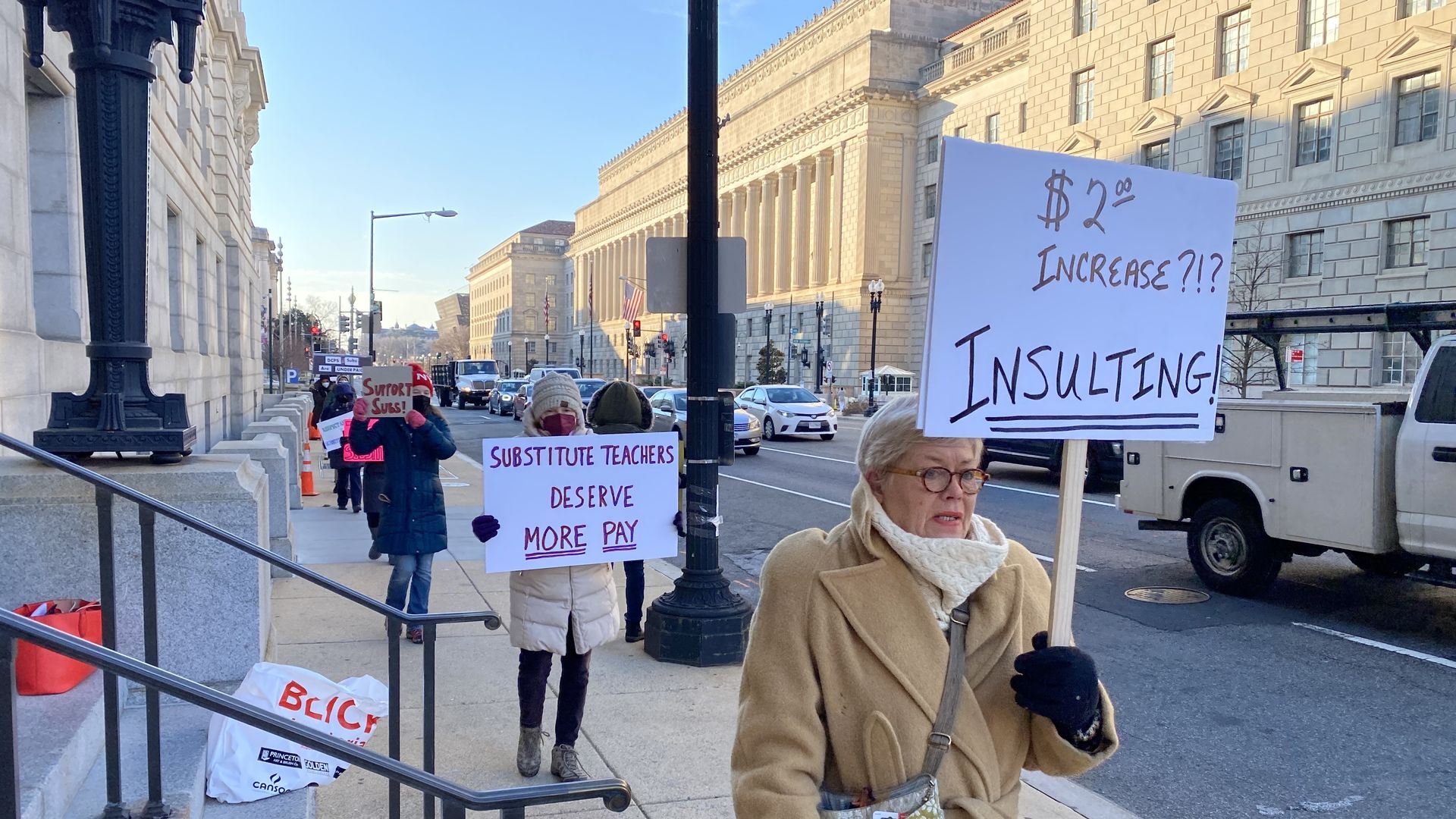A demonstrator holds a sign that calls for more pay for substitute teachers in D.C.