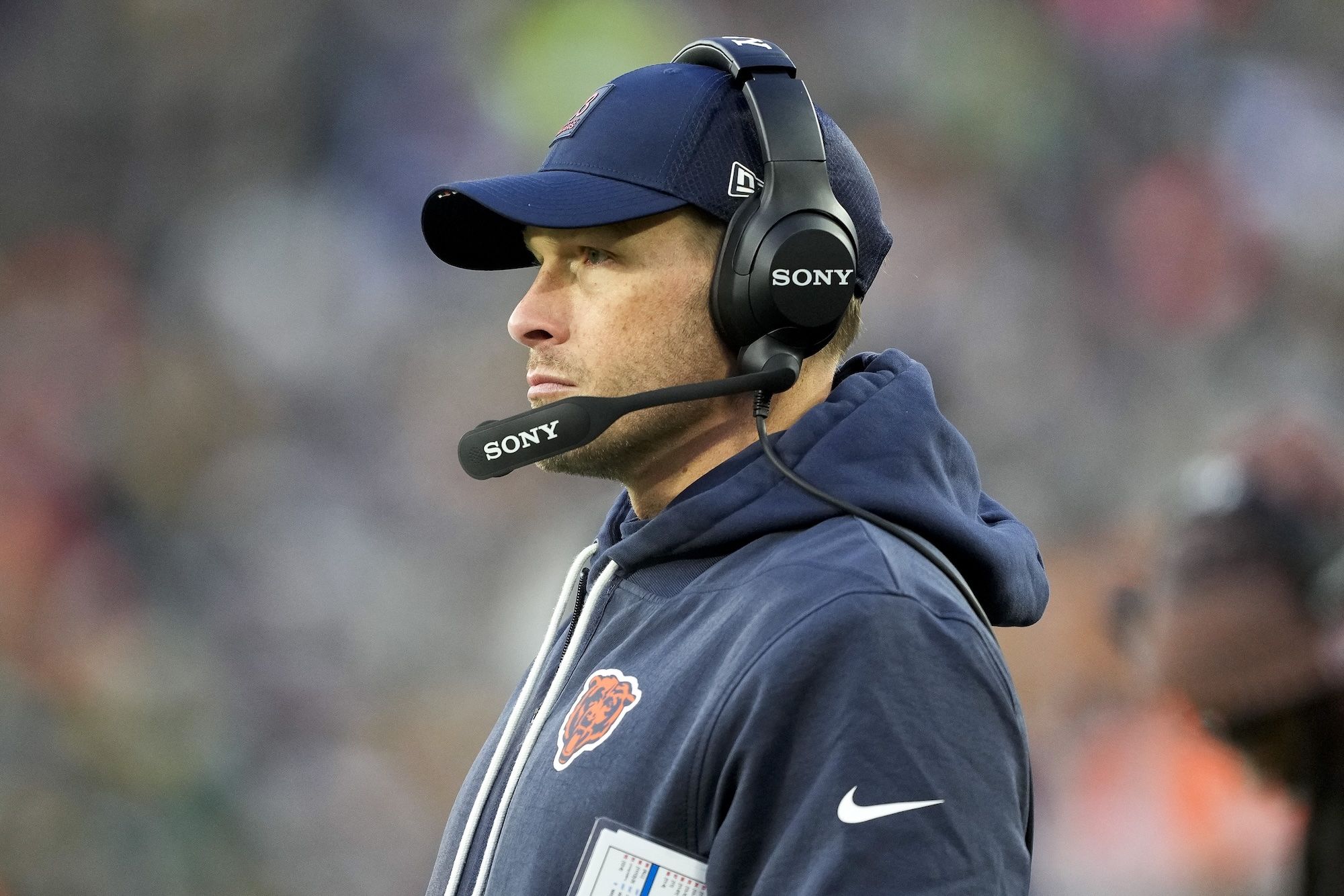 Chicago Bears coach Ben Johnson wearing a Sony head set and Bears hoodie and hat.