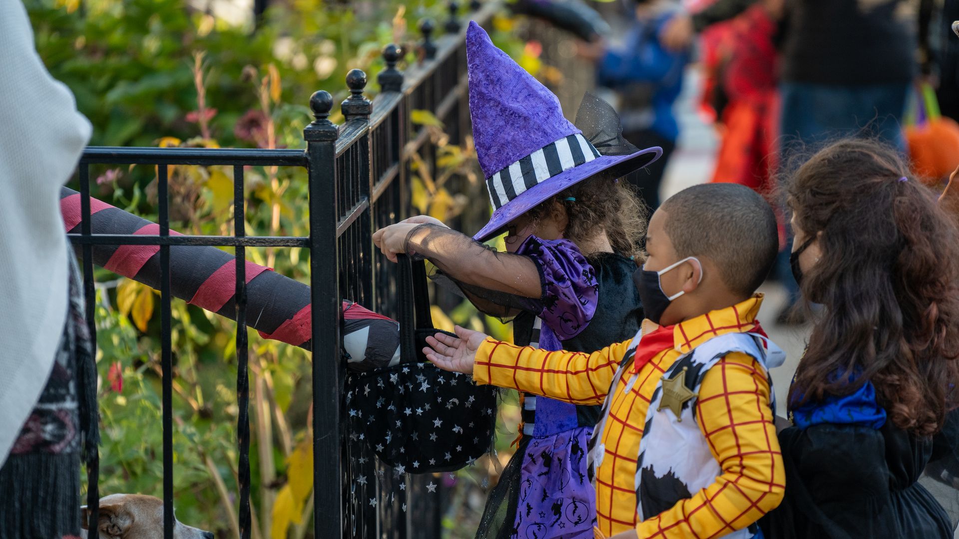 Children receive treats by candy chutes while trick-or-treating for Halloween