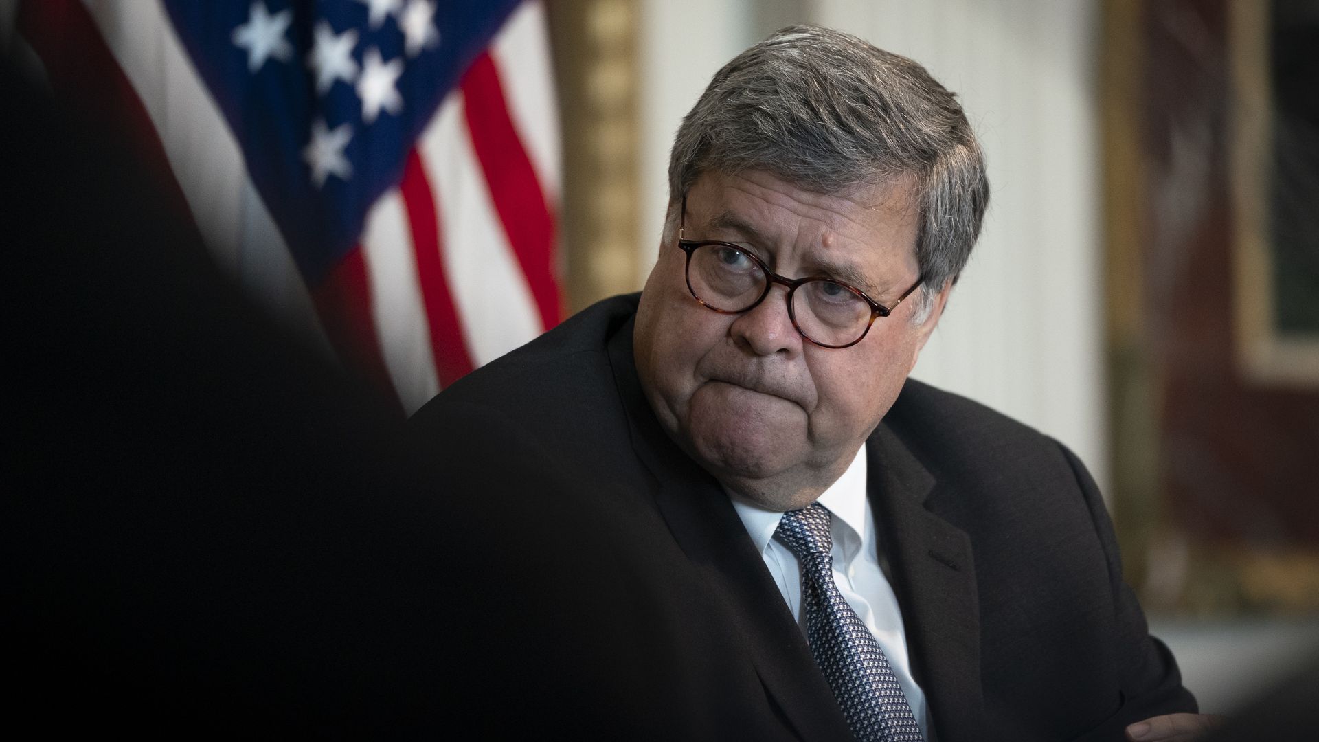 Bill Barr sits in front of an American flag