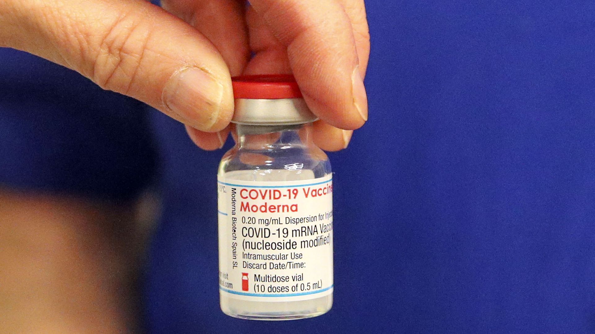 A vial of Moderna vaccine is held by a hand